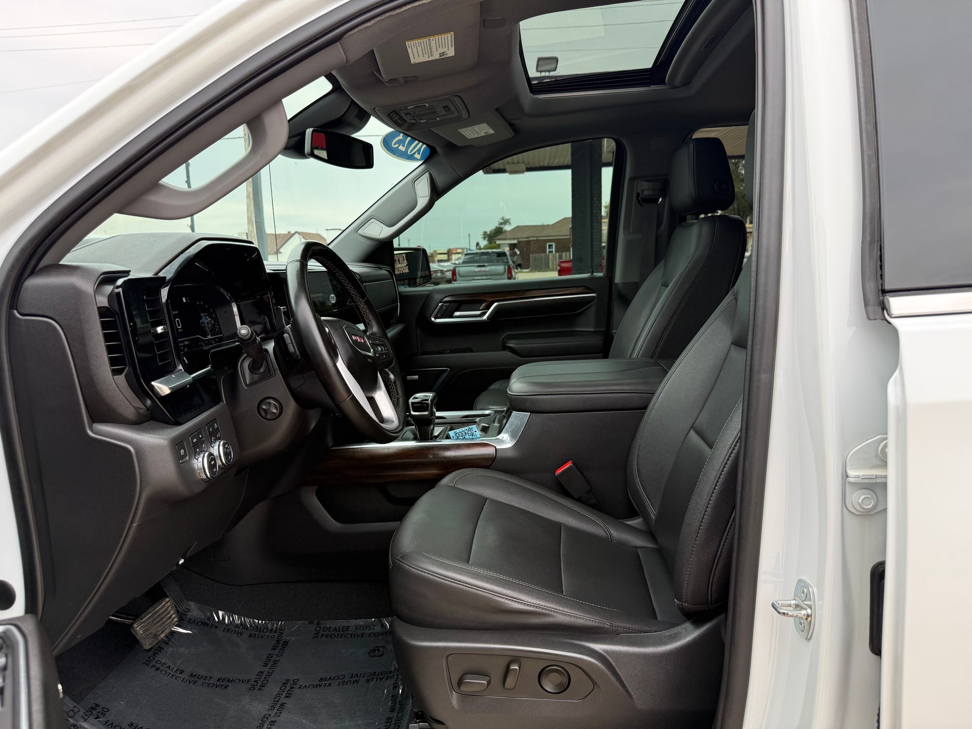 Interior of a white truck with black leather seats, a sunroof, and a view of the dashboard.