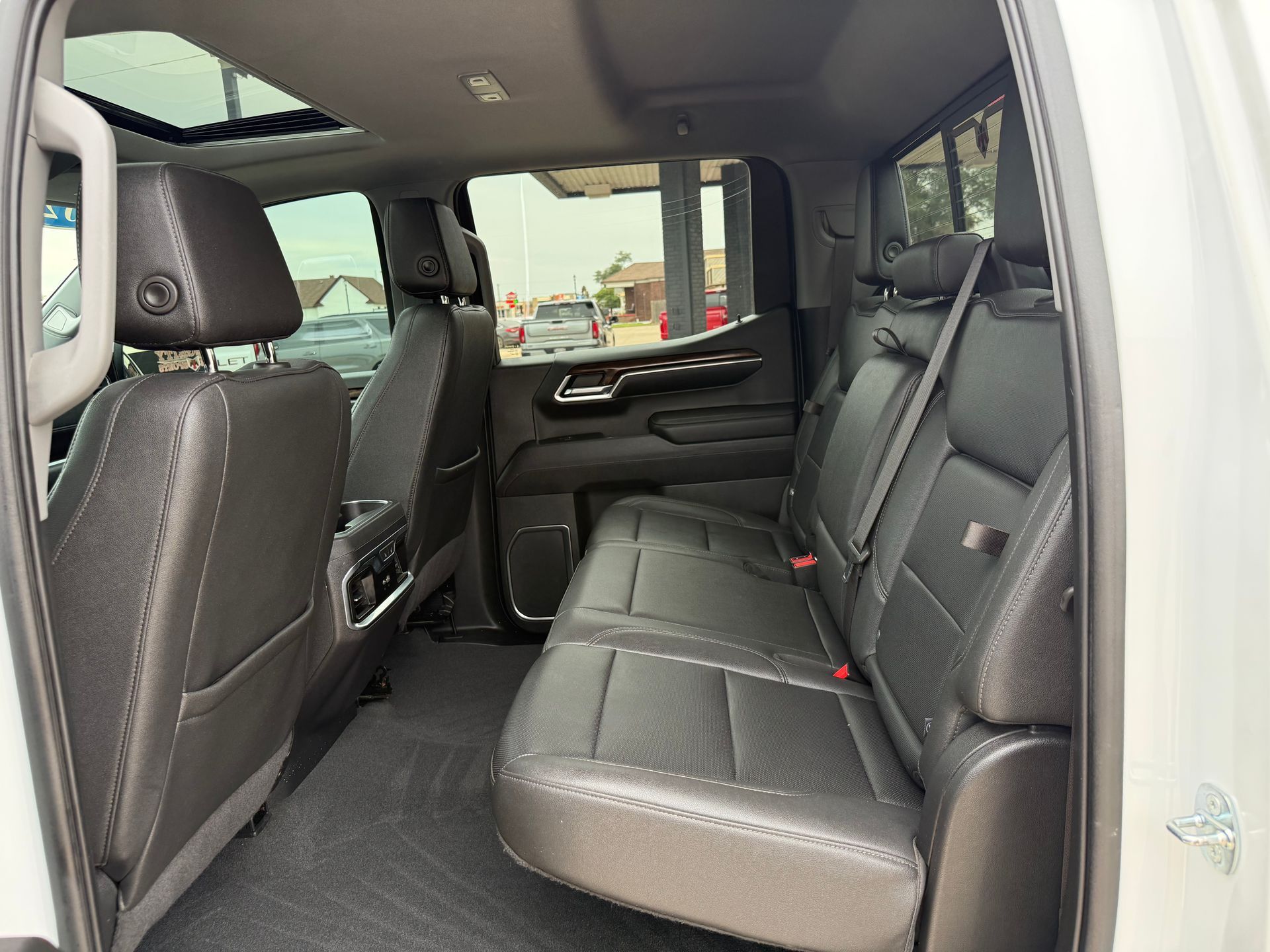 Interior view of a truck's back seat with black leather seats and a sunroof.