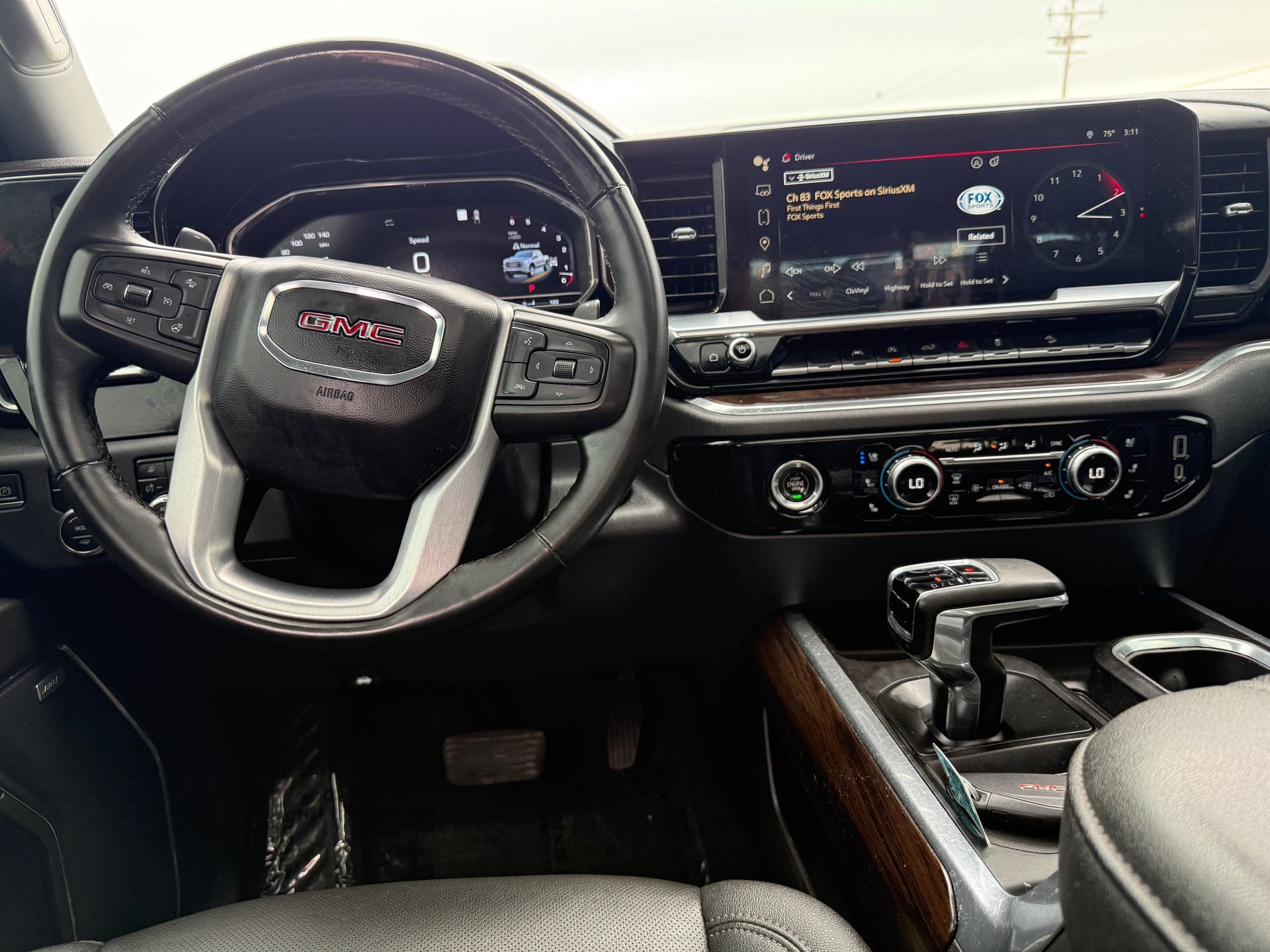 Interior of a GMC truck: black dashboard, steering wheel, digital display, and gear shift.