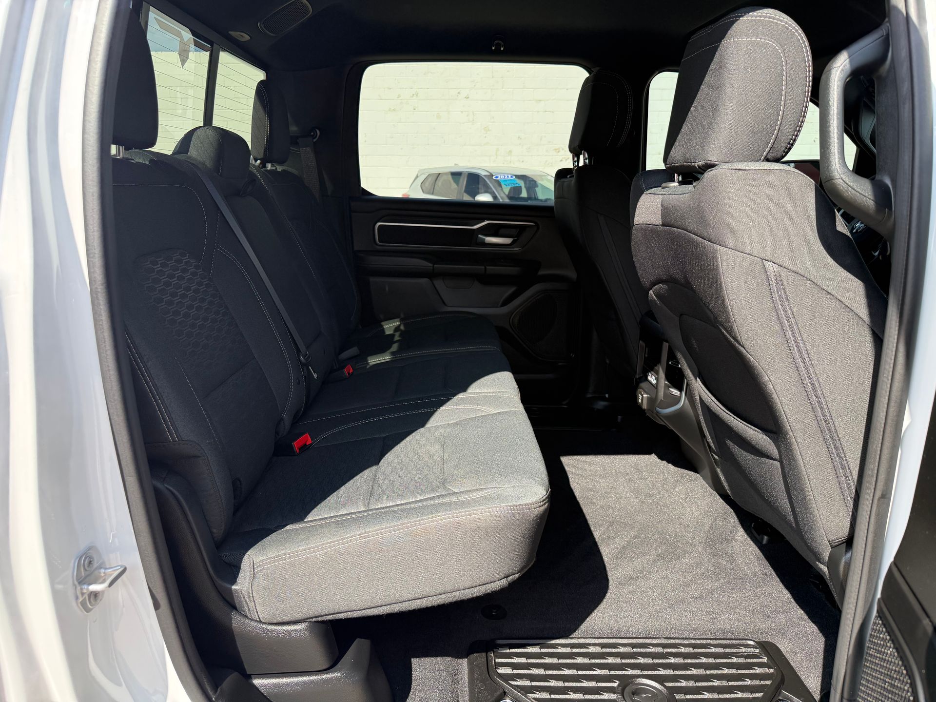 Back seat of a gray truck with black fabric seats, looking towards the back of the cab.