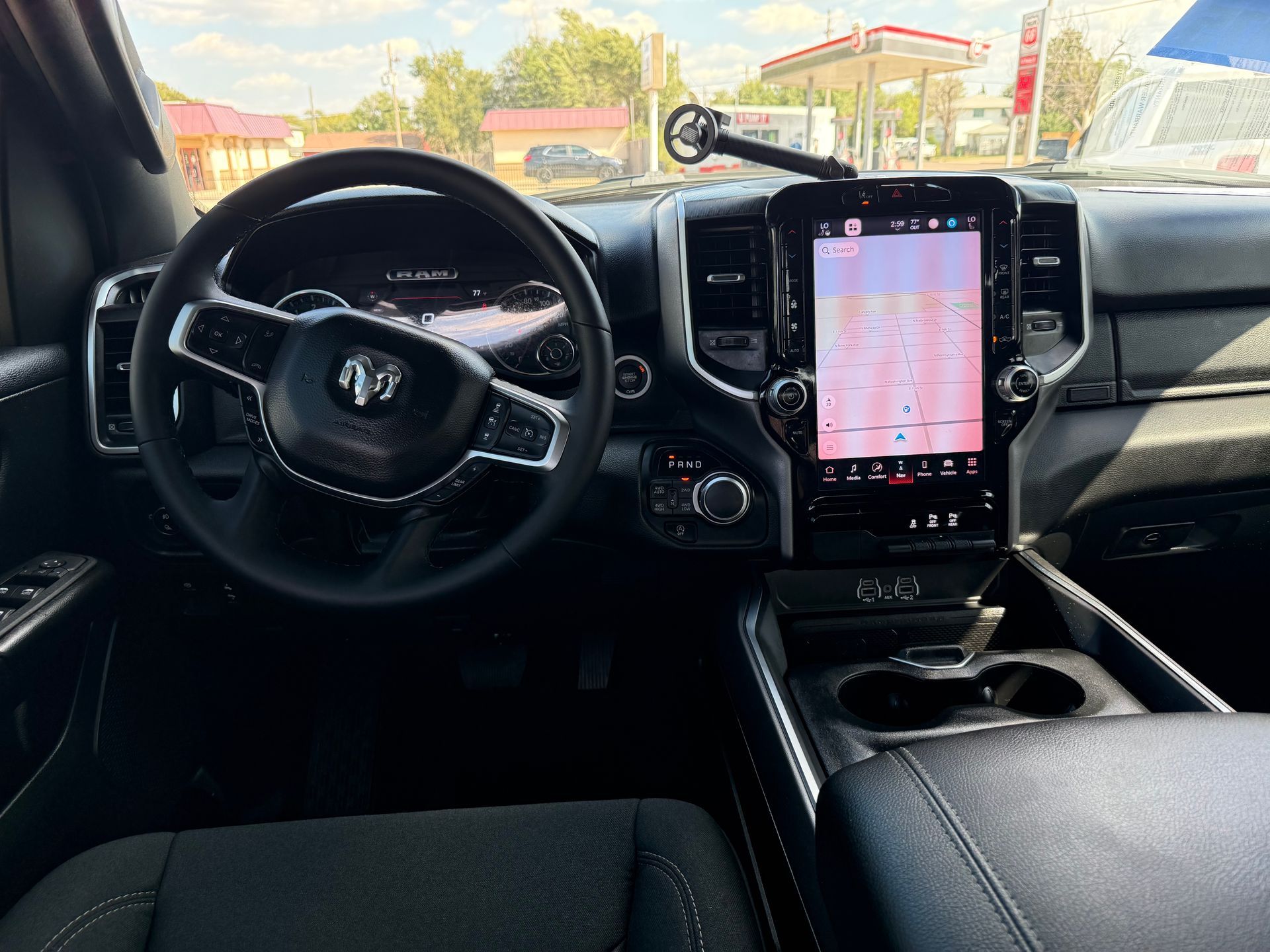Interior of a RAM truck. Black dashboard, steering wheel, and large touchscreen displaying a map.
