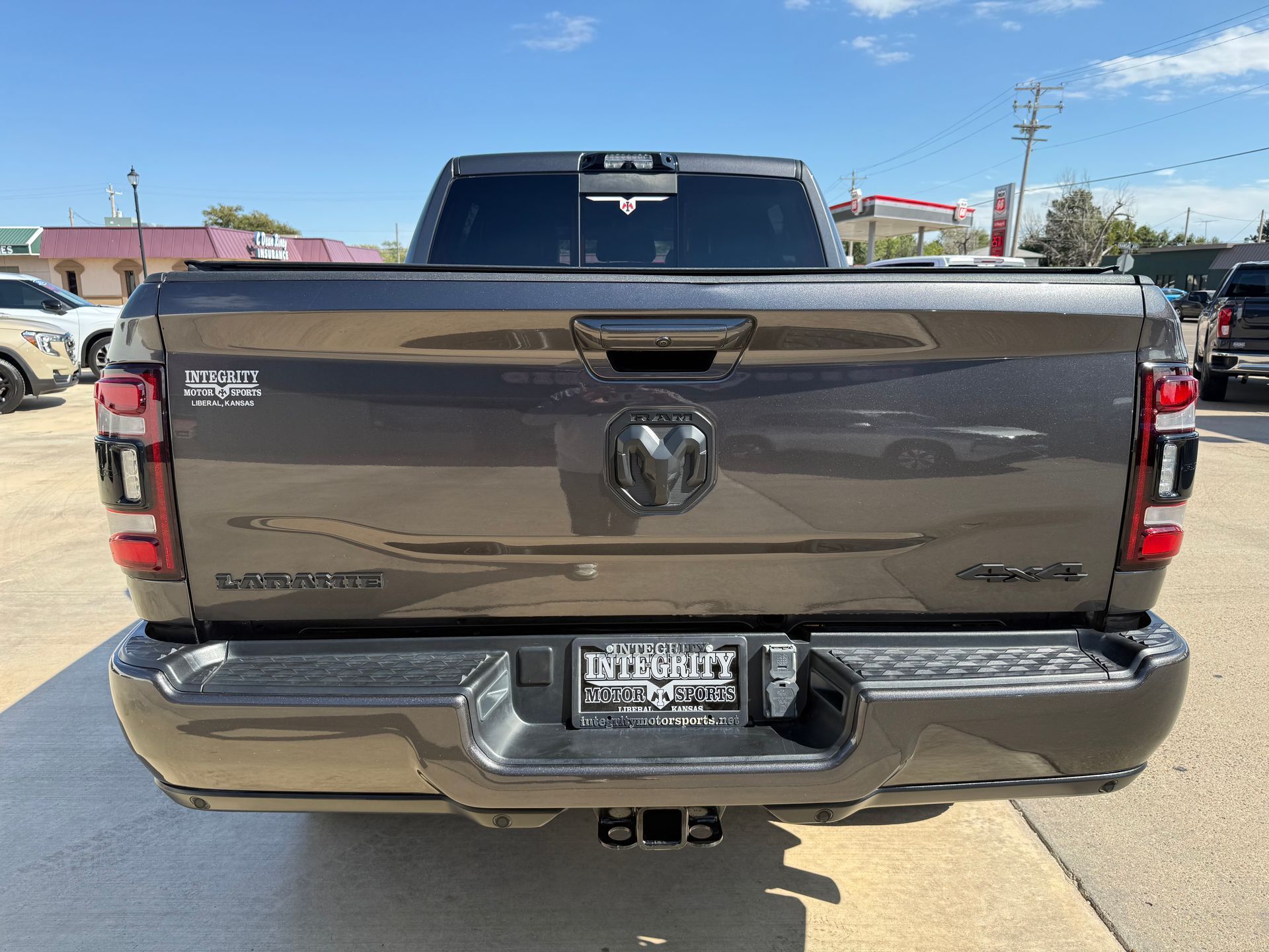 Dark gray Ram pickup truck, rear view, parked outdoors in a sunny setting.