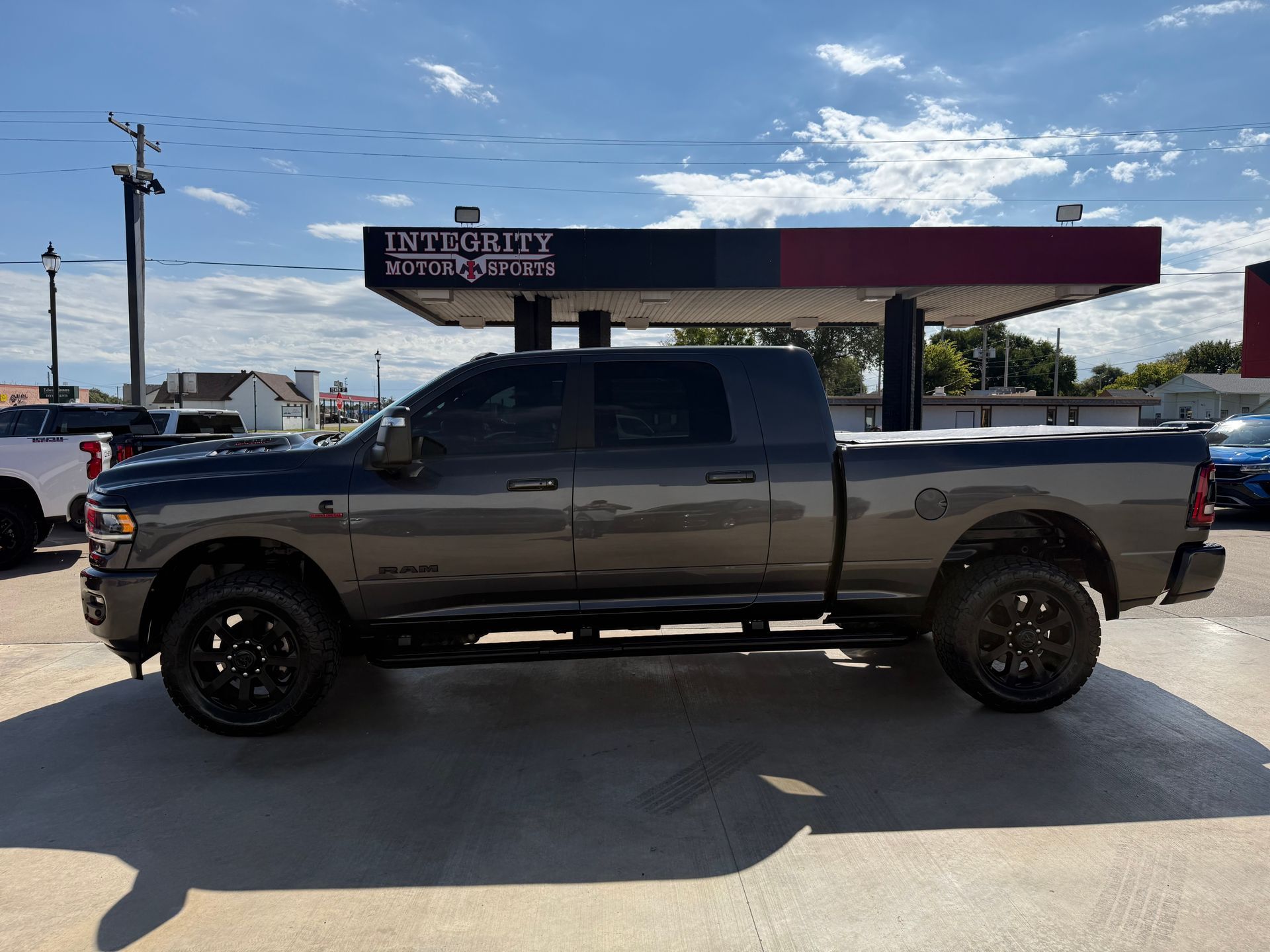 Gray Ram truck parked in front of a Unity Motors building on a sunny day.
