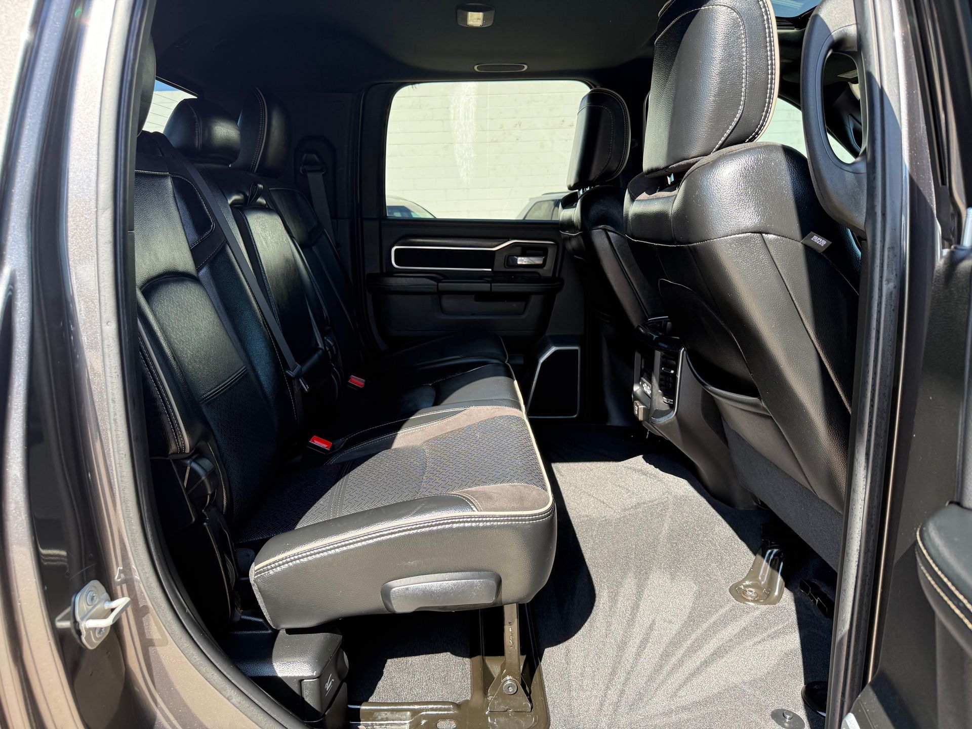 Inside of a black pickup truck, with back seats folded up. Dark interior, grey carpet.
