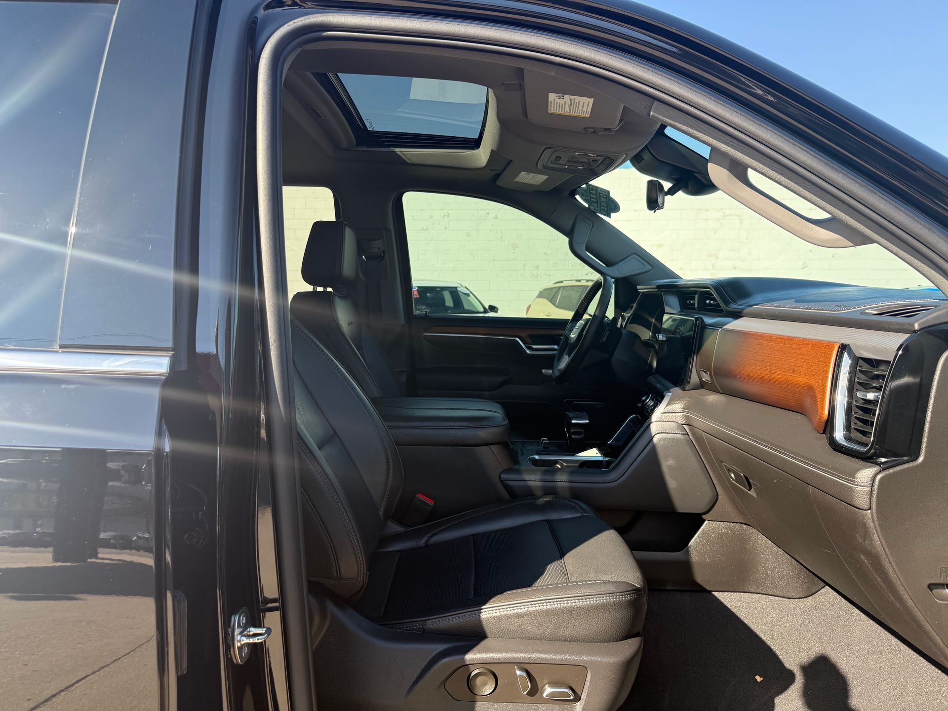 Interior of a dark gray SUV with black leather seats, wood trim, and a sunroof.