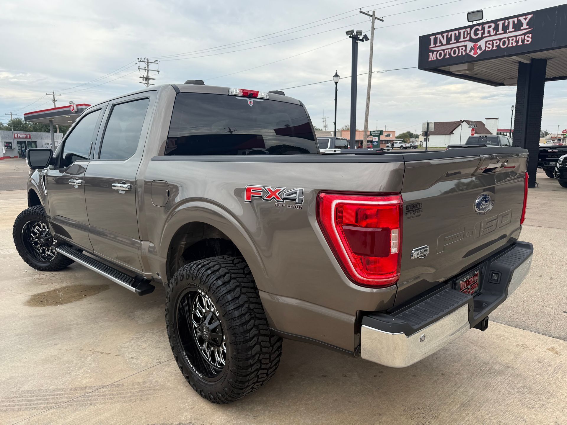 Brown Ford F-150 truck with black rims and FX4 decal parked at Integrity Motor Sports dealership.