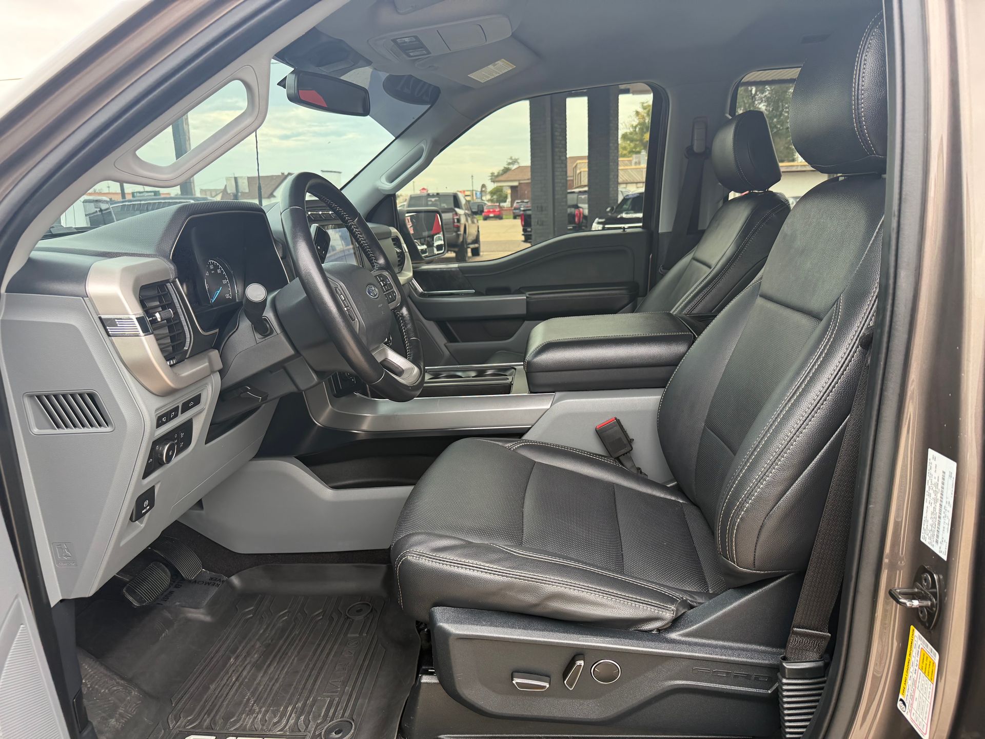 Interior view of a Ford truck with black leather seats, steering wheel, and dashboard.