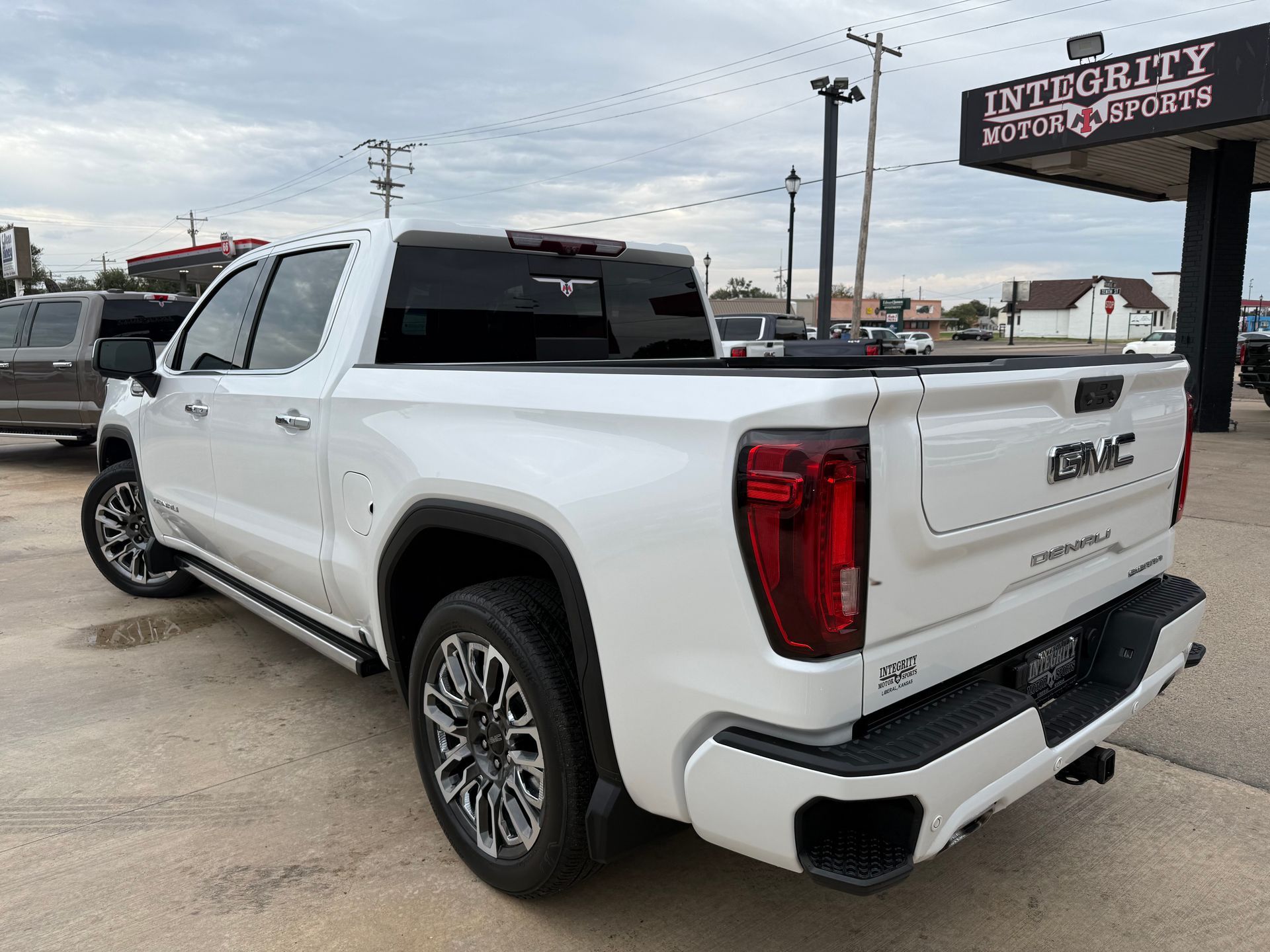 White GMC Sierra truck parked outside an auto dealership.