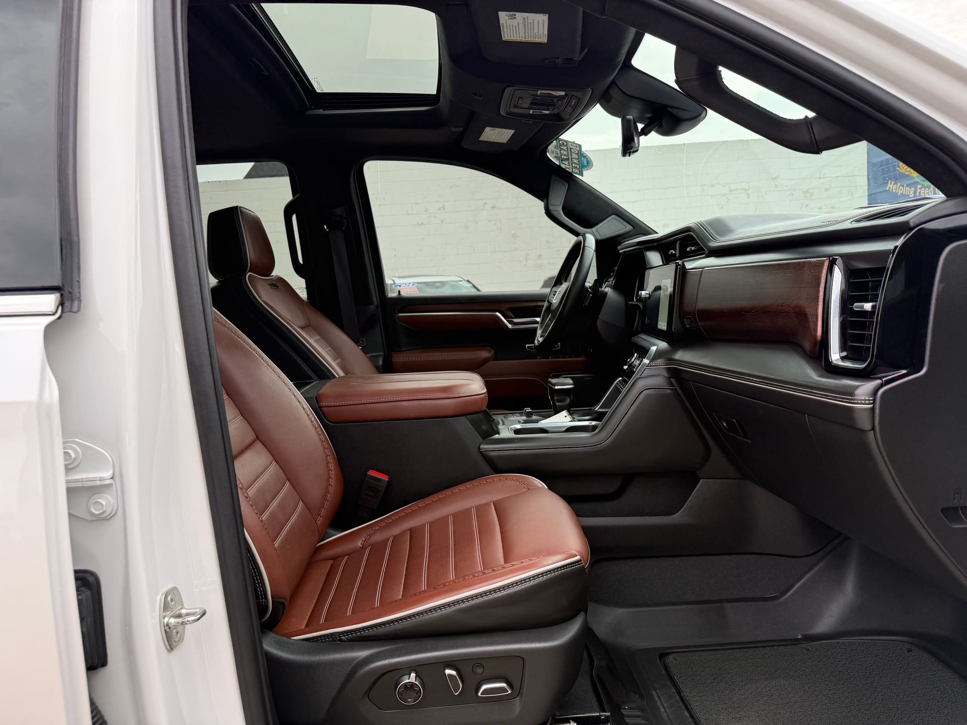 Interior view of a light-colored pickup truck with brown leather seats, black dashboard and sunroof.