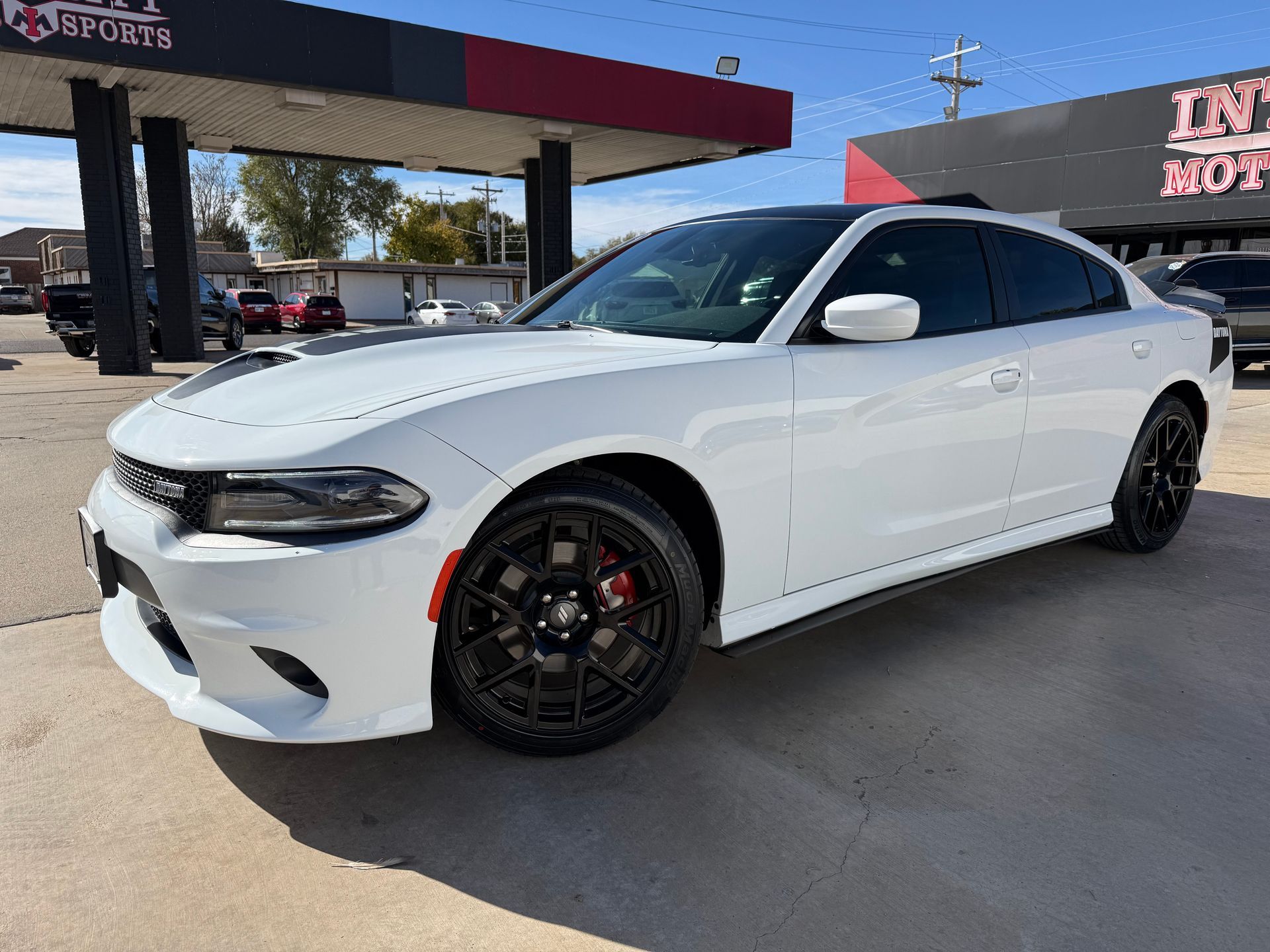 Red Nissan Altima sedan parked at a car dealership on a sunny day.
