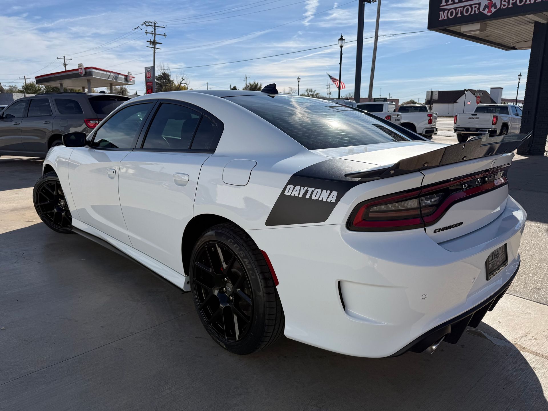 White Dodge Charger Daytona with black accents parked outside a business on a sunny day.