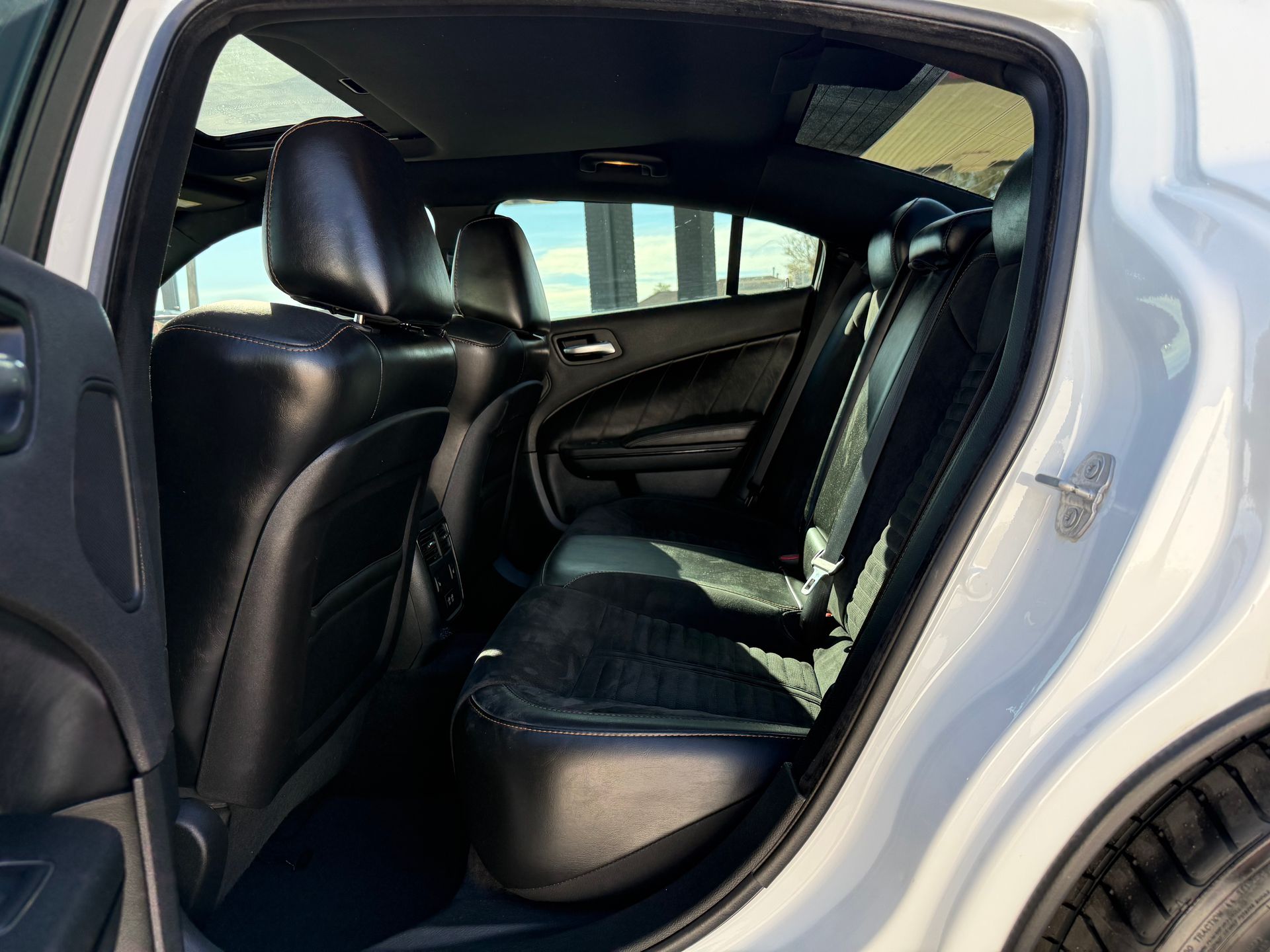 Interior of a white car, showcasing black leather rear seats and a partially visible sunroof.