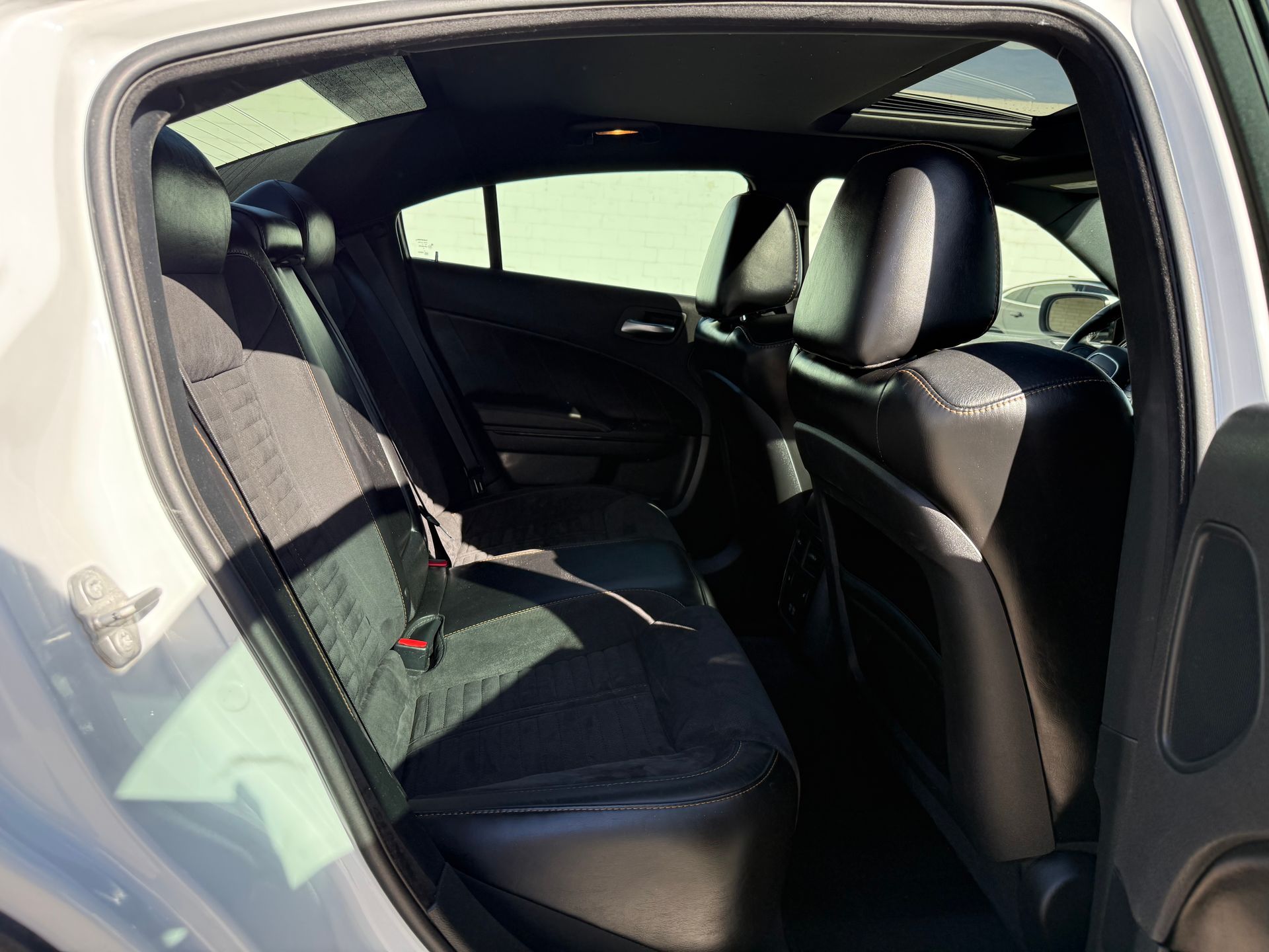 Back interior of a white car, showing black cloth rear seats.