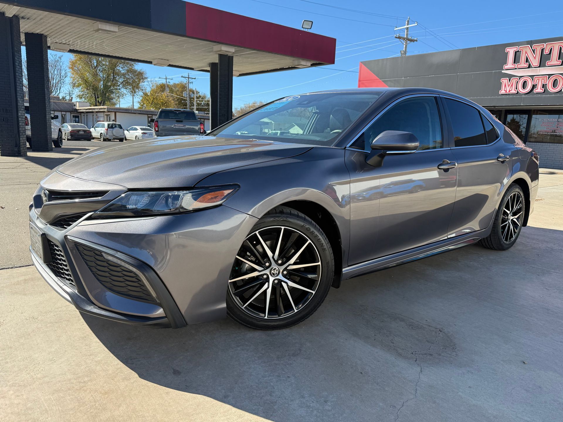 Red Nissan Altima sedan parked at a car dealership on a sunny day.