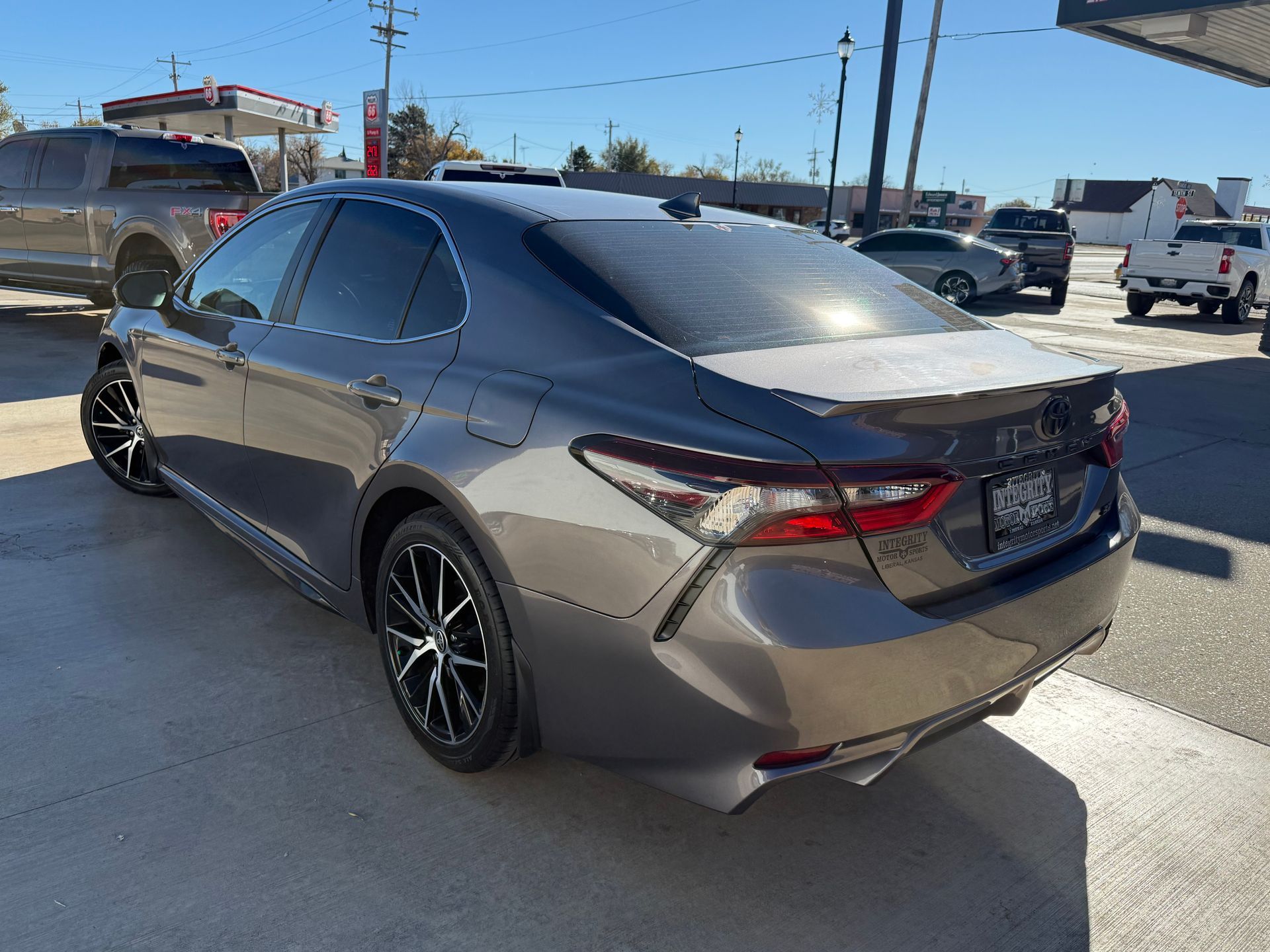 Gray Toyota Camry with black wheels parked outside on a sunny day.