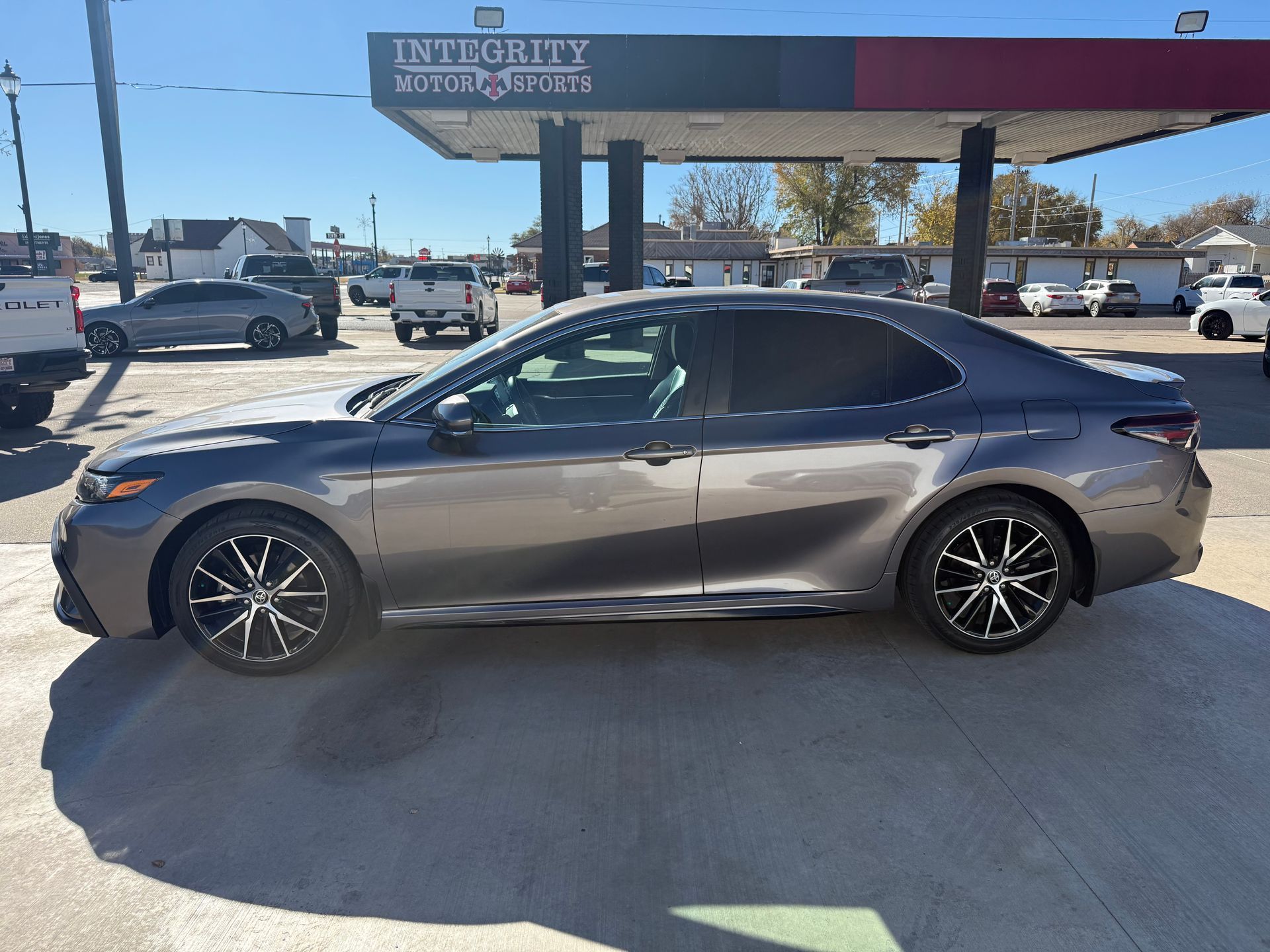 Gray Toyota Camry parked in front of a gas station under a blue sky.