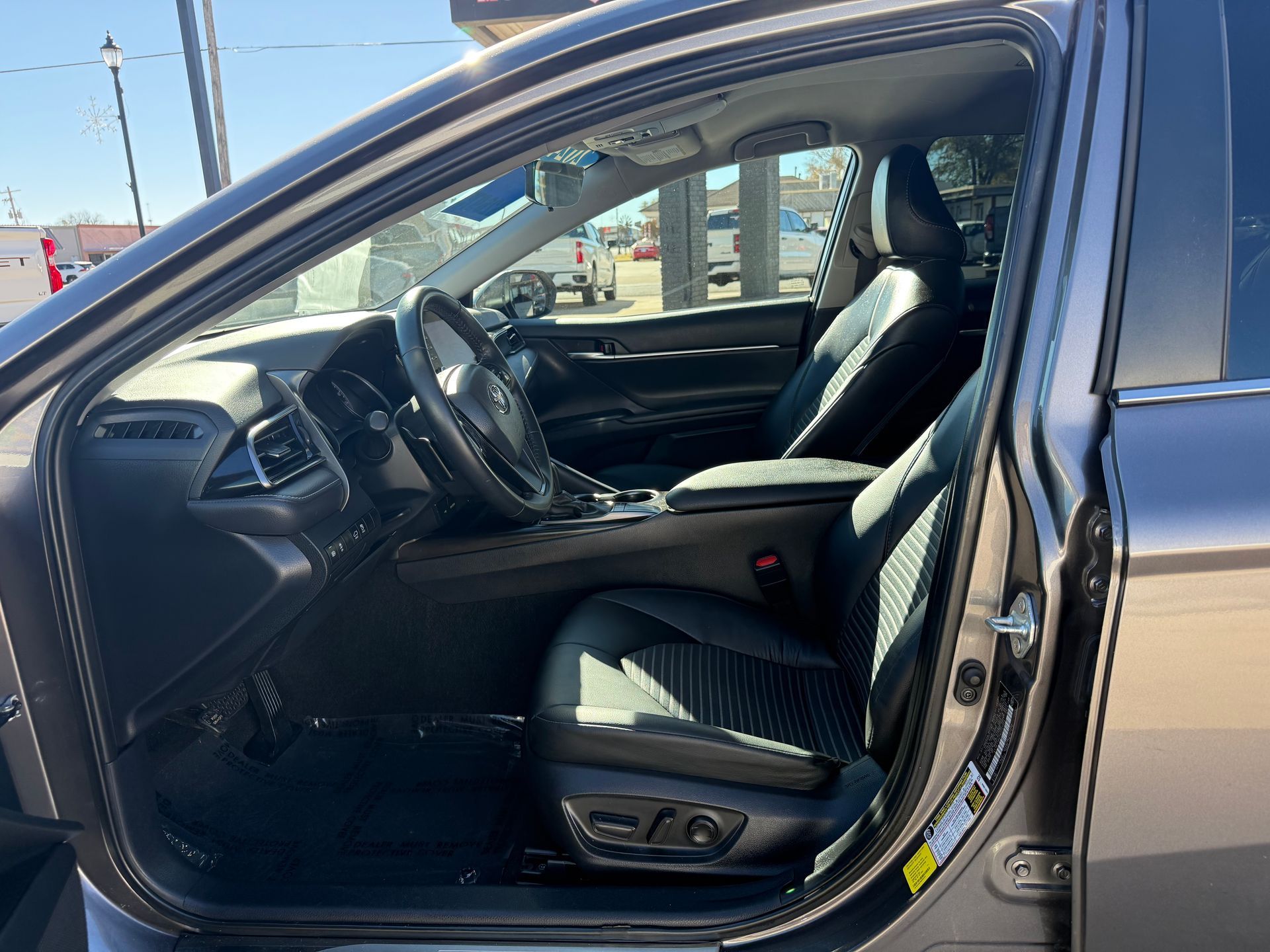 Gray Toyota Camry interior, driver's side open, black leather seats, dashboard, and steering wheel visible.