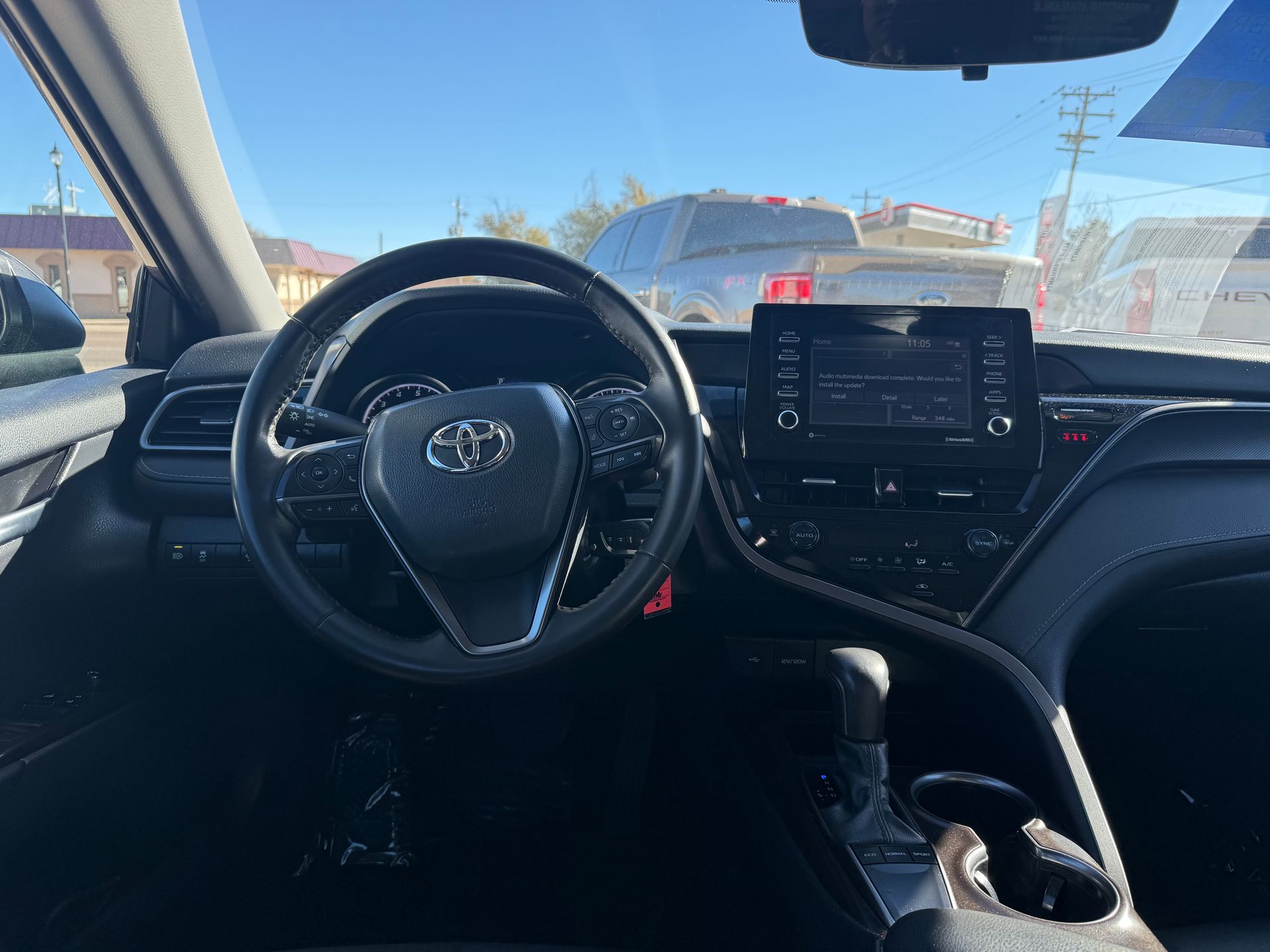 Interior of a Toyota Camry, showing the steering wheel, dashboard, and infotainment screen.