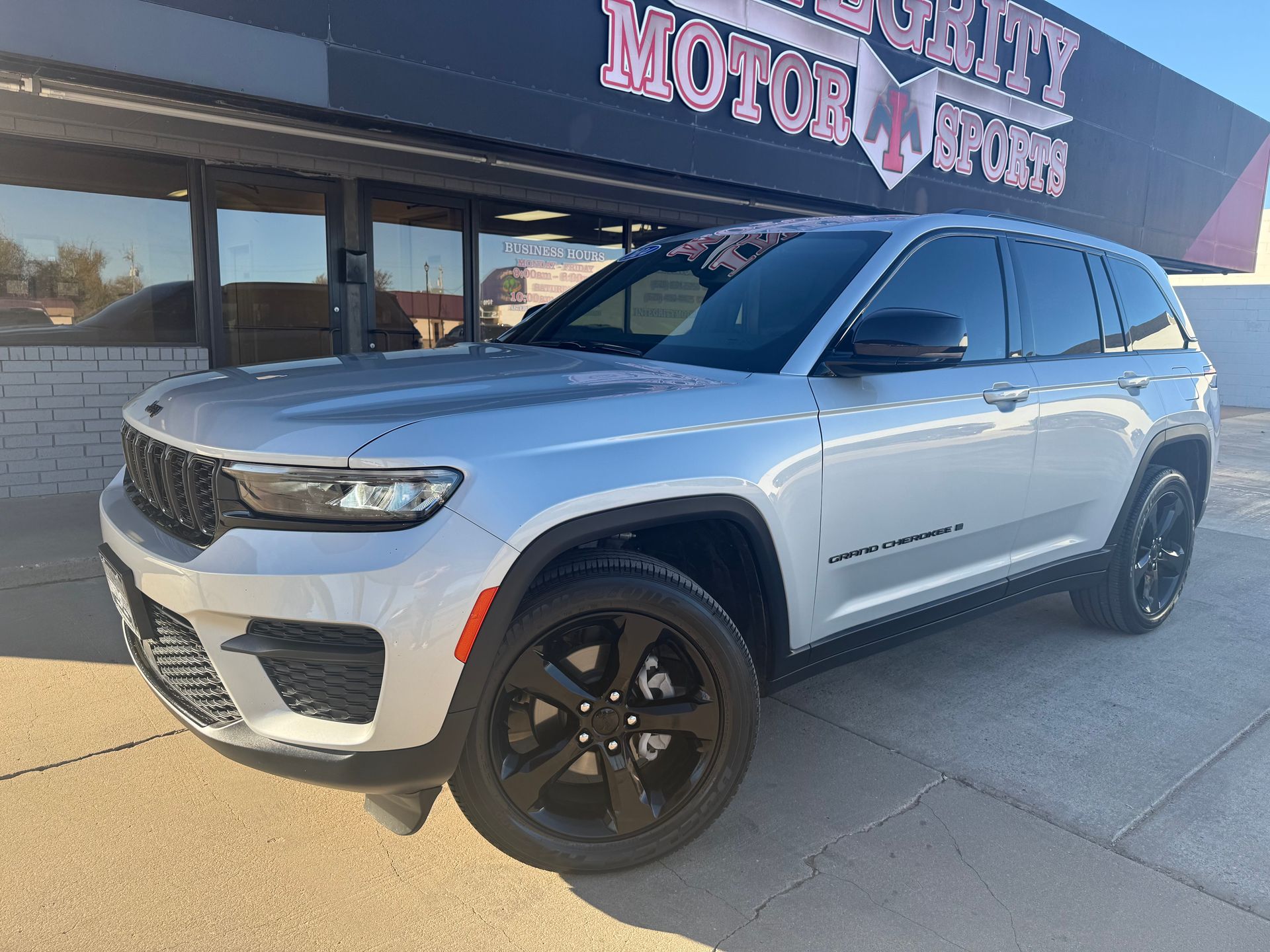 Black Buick Enclave SUV parked on a sunny day in front of an auto shop.