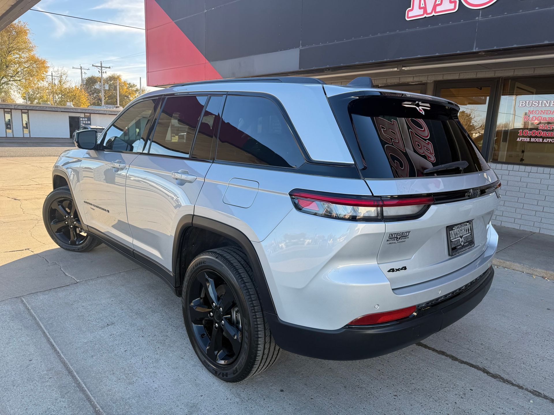 Silver SUV with black wheels parked outside a business building.