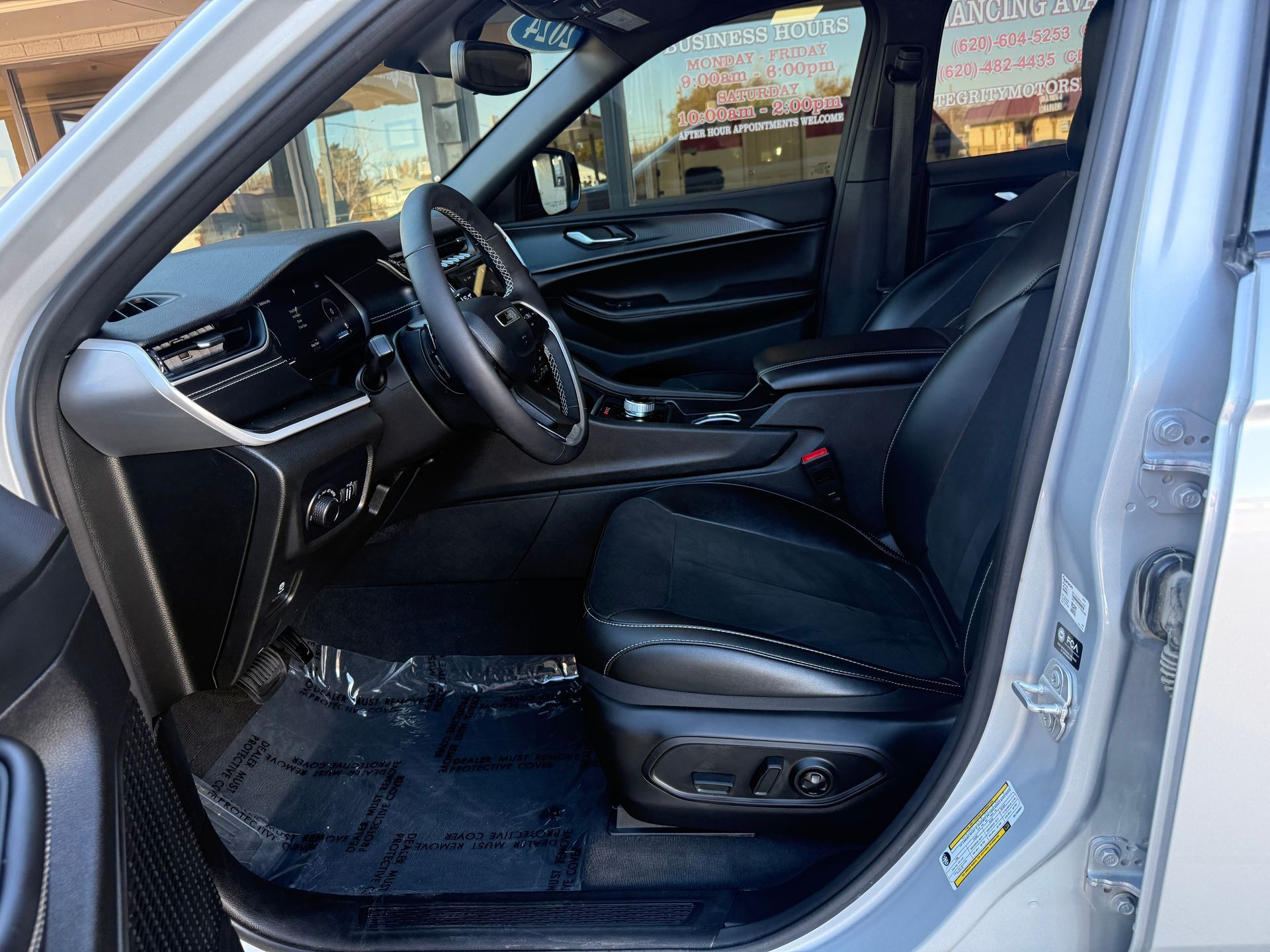 Interior view of a silver SUV with black leather seats, steering wheel, and floor mats.