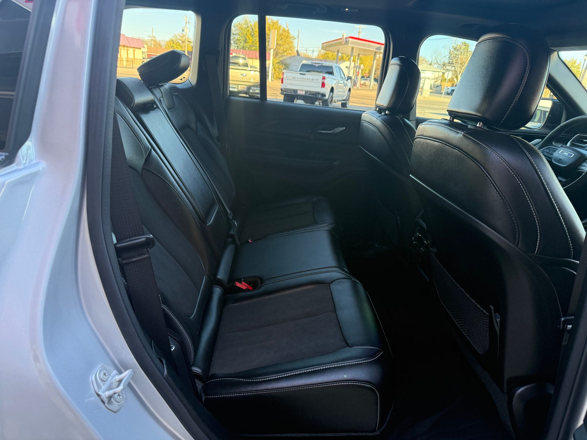 Back seat interior of a car with black leather seats, facing forward.