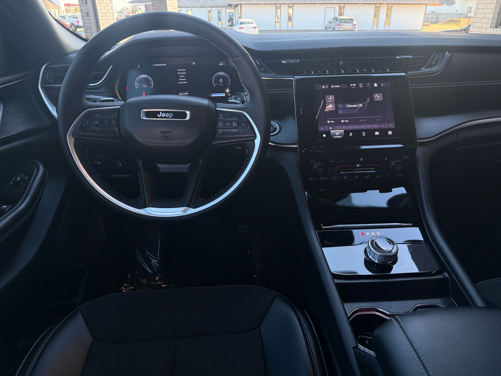 Interior of a black car, dashboard with steering wheel, digital displays, and center console.