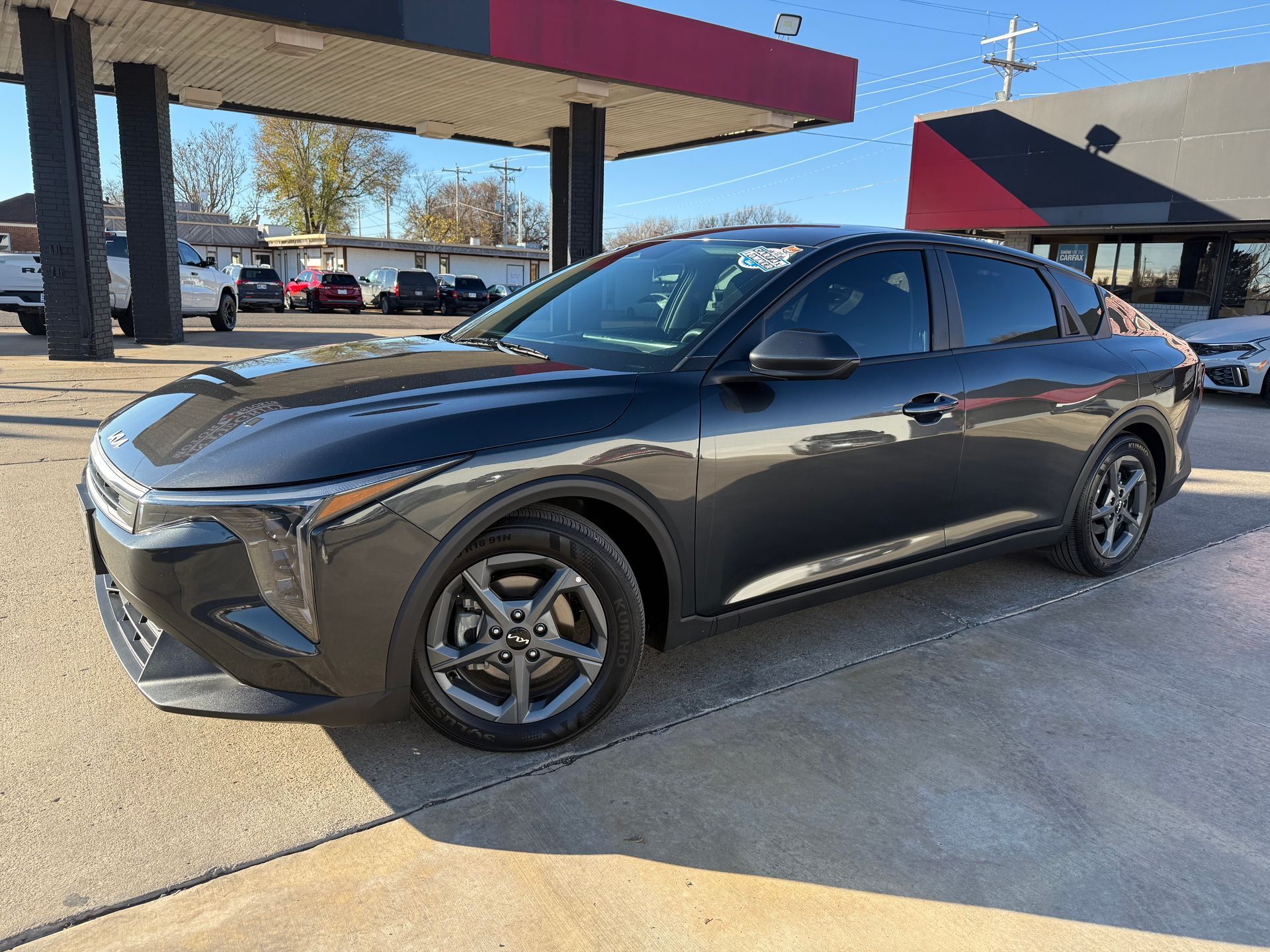 Red Nissan Altima sedan parked at a car dealership on a sunny day.