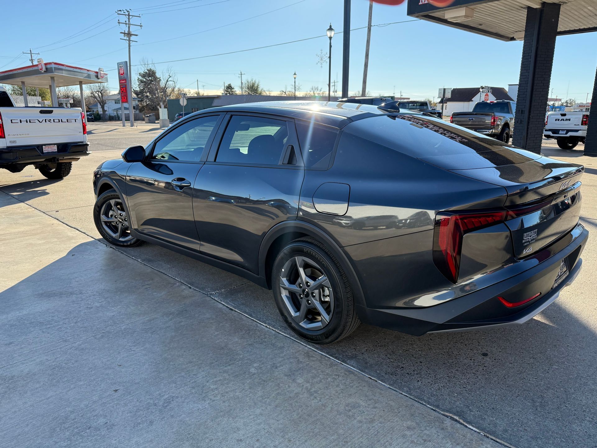Dark gray electric SUV parked in a gas station lot on a sunny day.