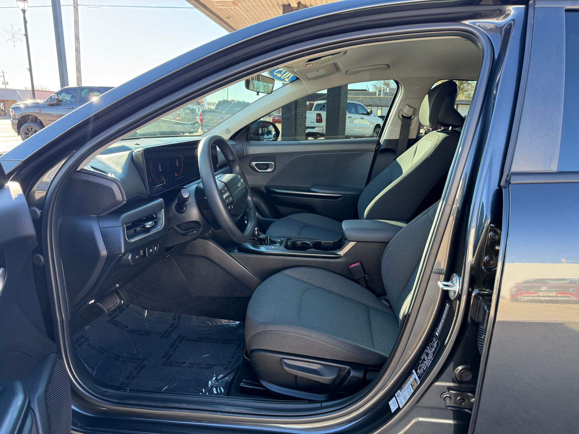 Interior of a black car with gray seats; driver's side door open, dashboard and steering wheel visible.