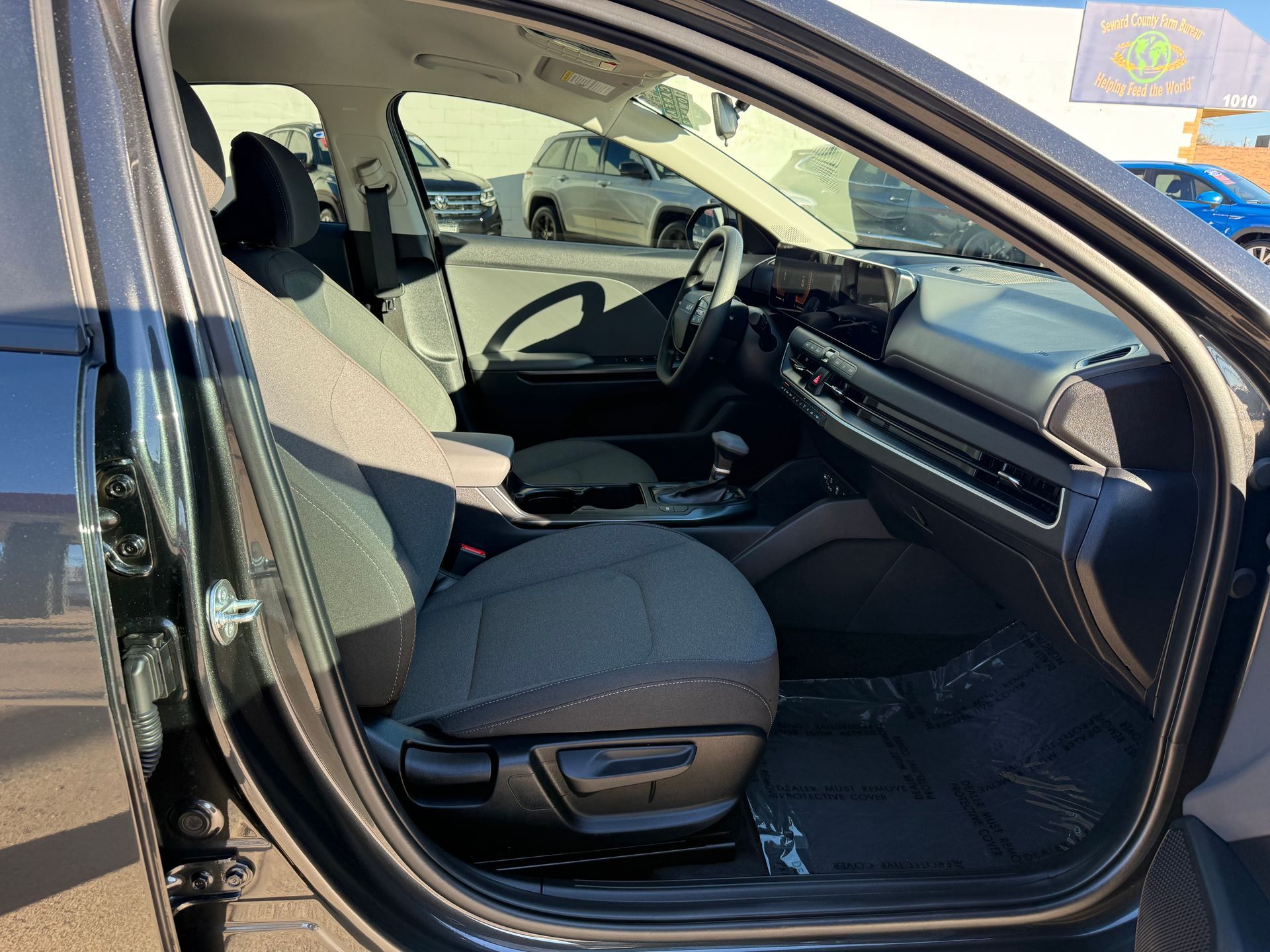 Interior view of a gray car with cloth seats and dashboard; door is open, showing the inside.