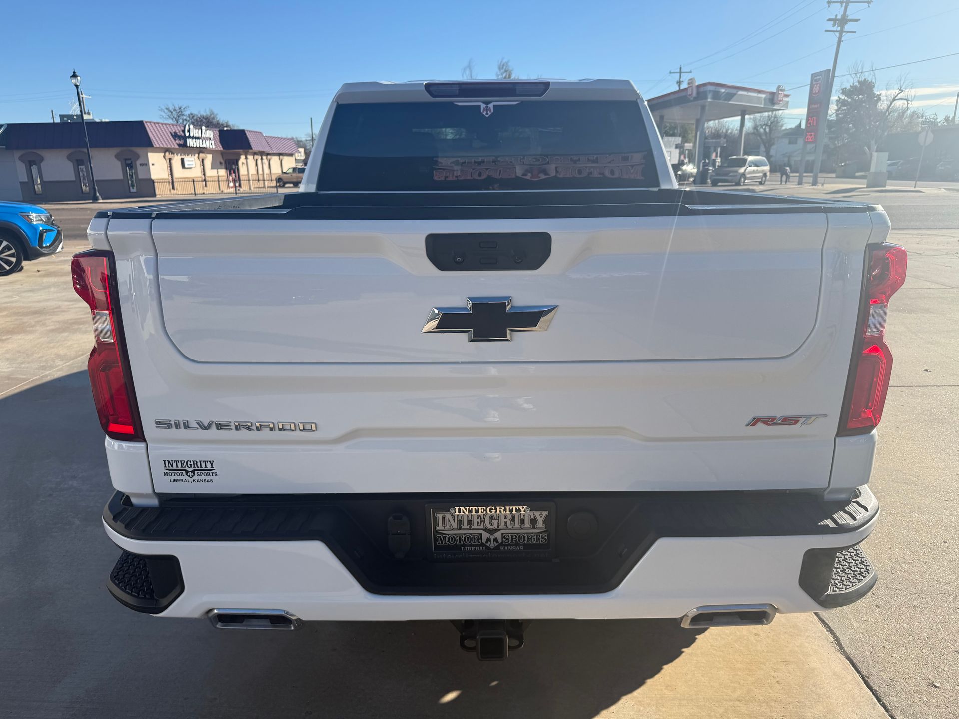 White Chevrolet Silverado truck, rear view, parked on a sunny day.
