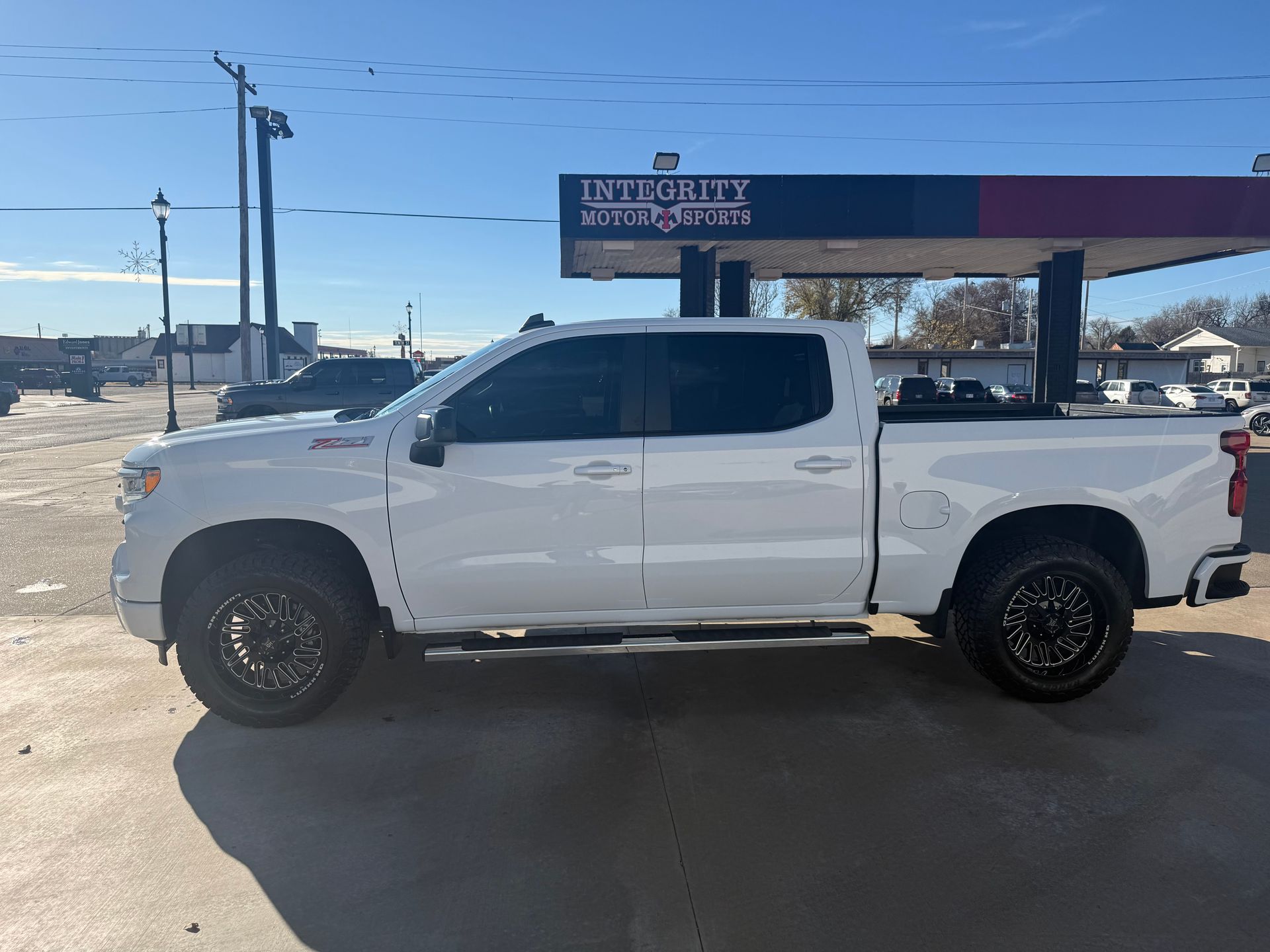 White pickup truck parked outside a gas station on a sunny day.