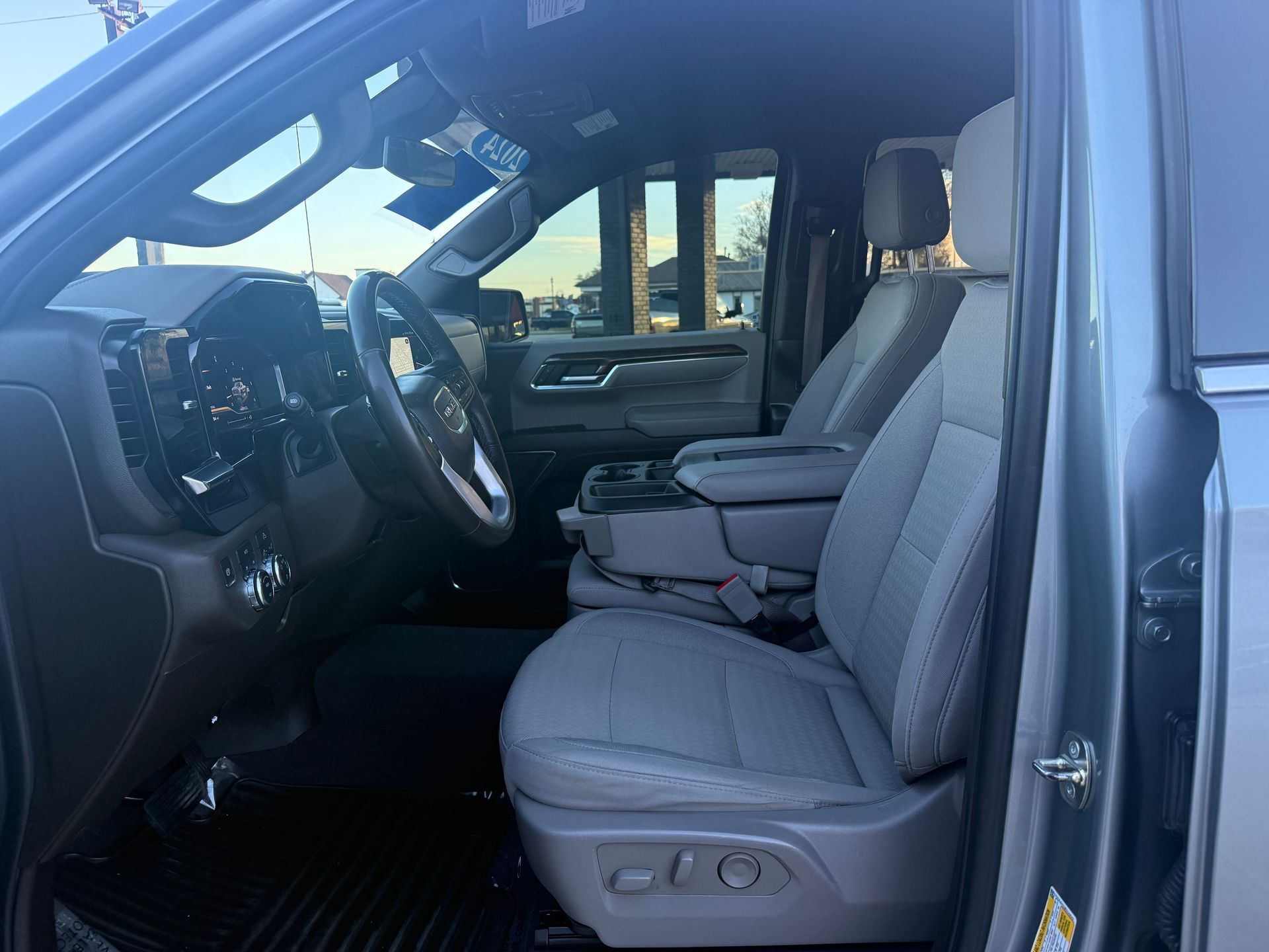 Interior view of a light blue truck, driver's seat visible. Grey seats, steering wheel, and dashboard.