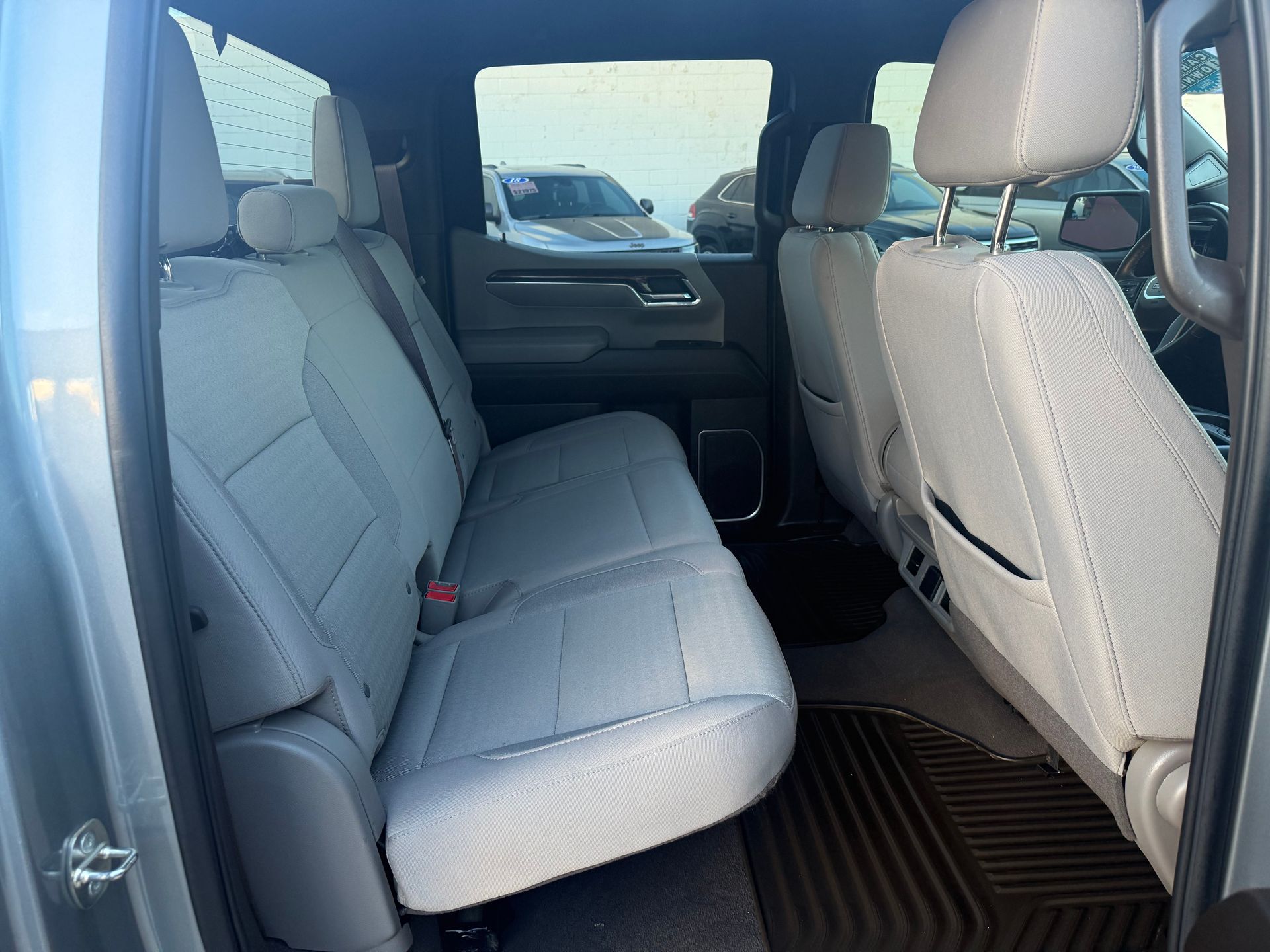 Interior view of a light gray pickup truck's back seat with headrests and black floor mats.