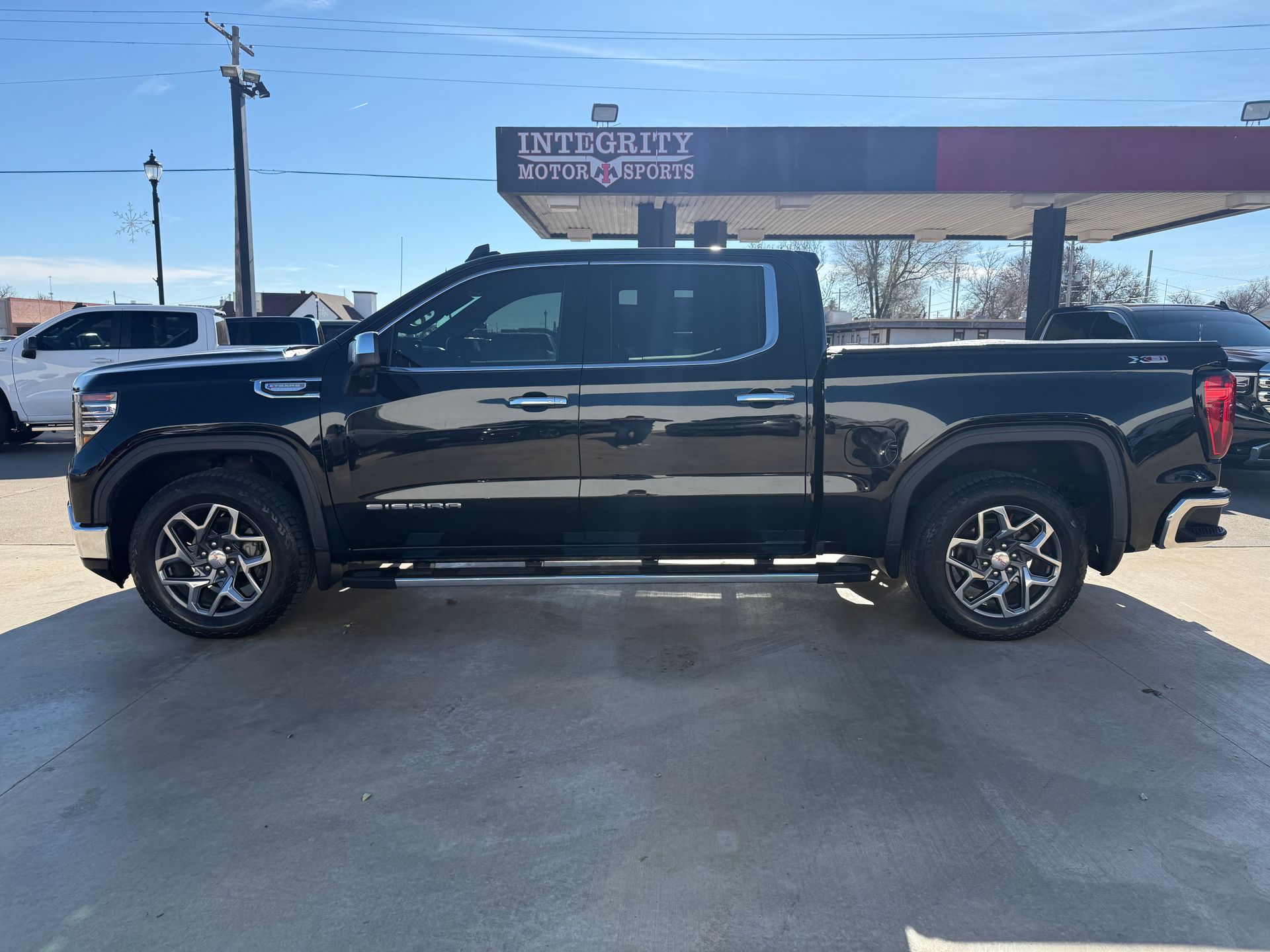 Black GMC pickup truck parked outside a gas station on a sunny day.
