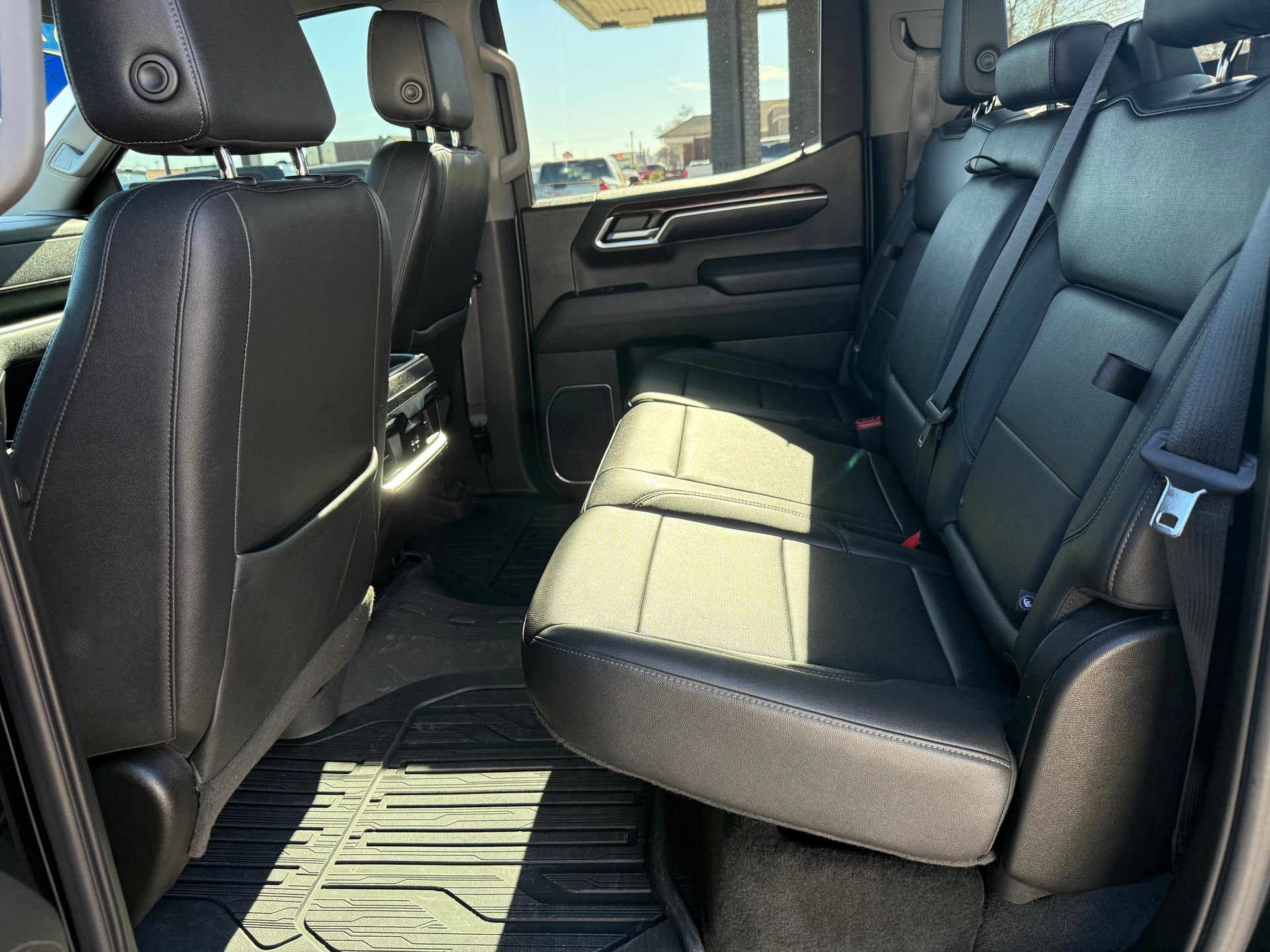 Black leather truck seats; rear interior view with floor mats.