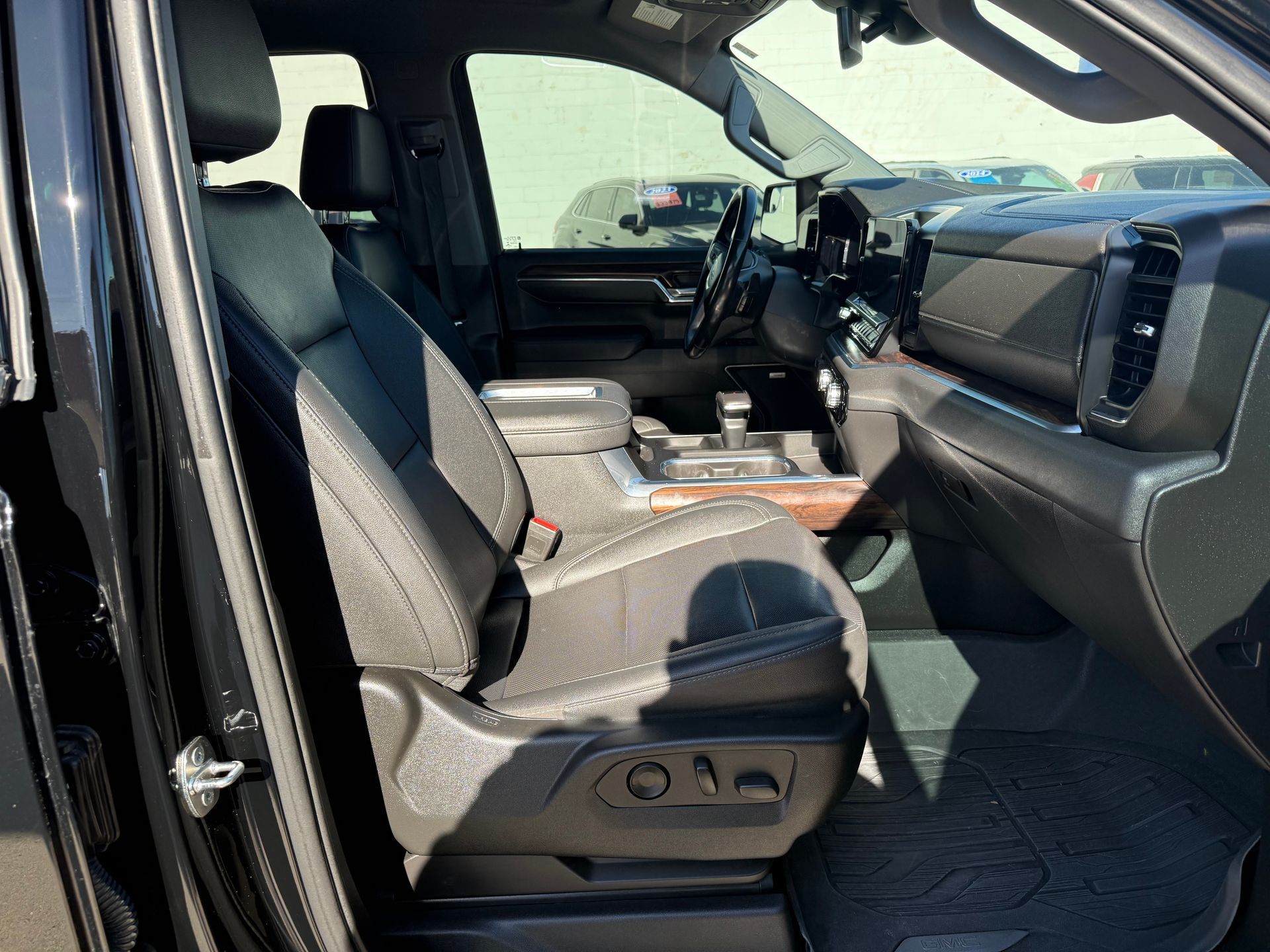 Interior of a black truck. Front seat is visible with console and dashboard. Sunlight.