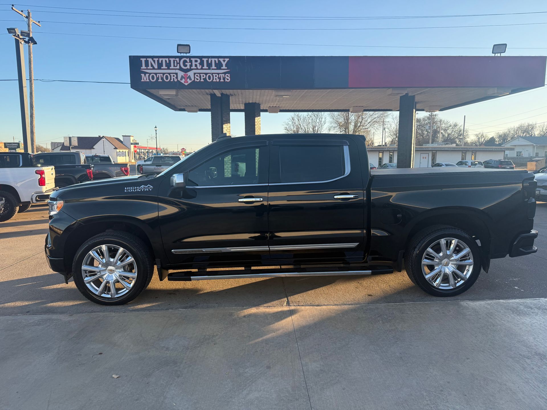 Black pickup truck parked at a gas station with chrome wheels and trim.