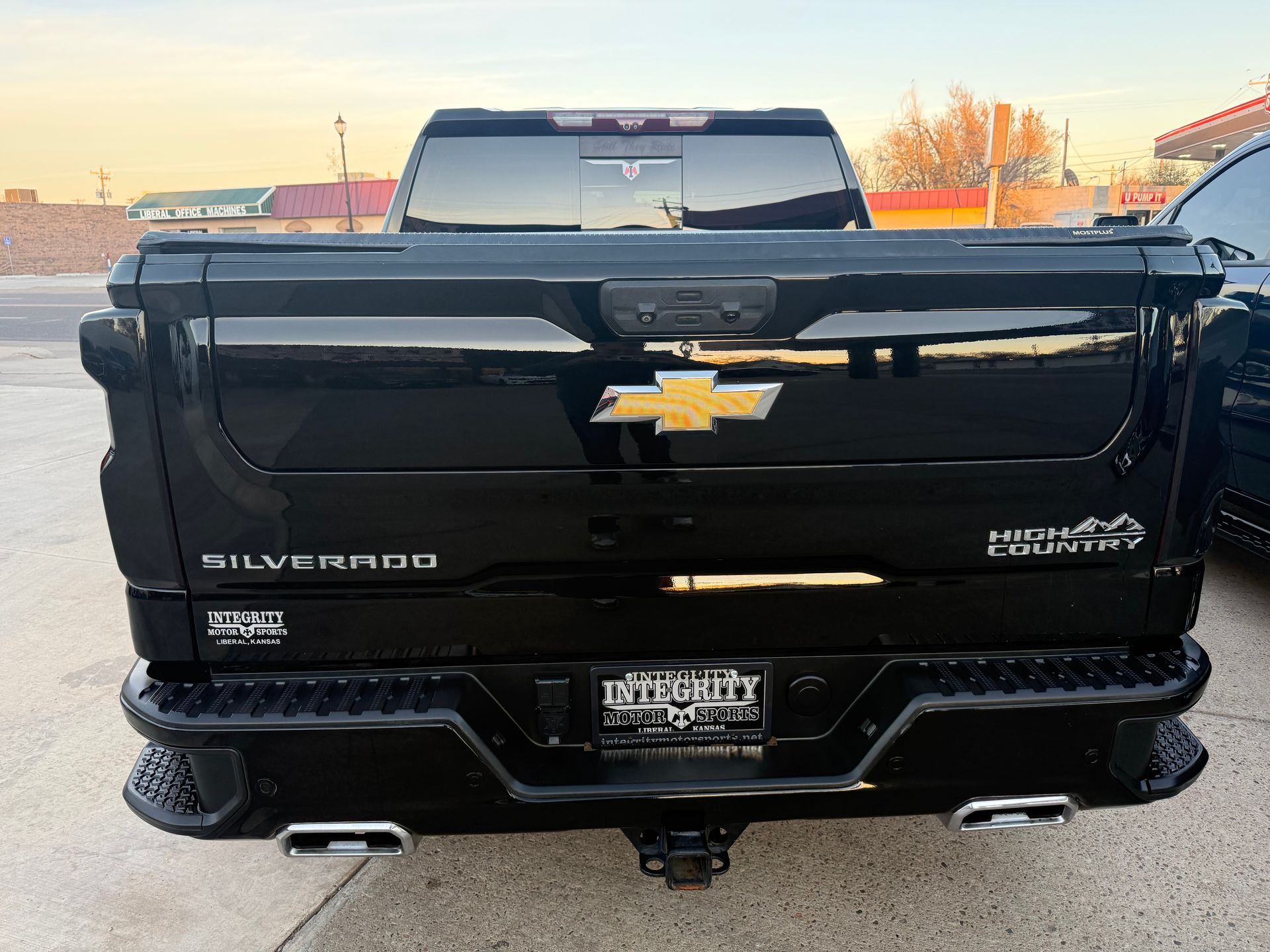 Black Chevrolet Silverado truck rear view, with tailgate logo and exhaust tips.
