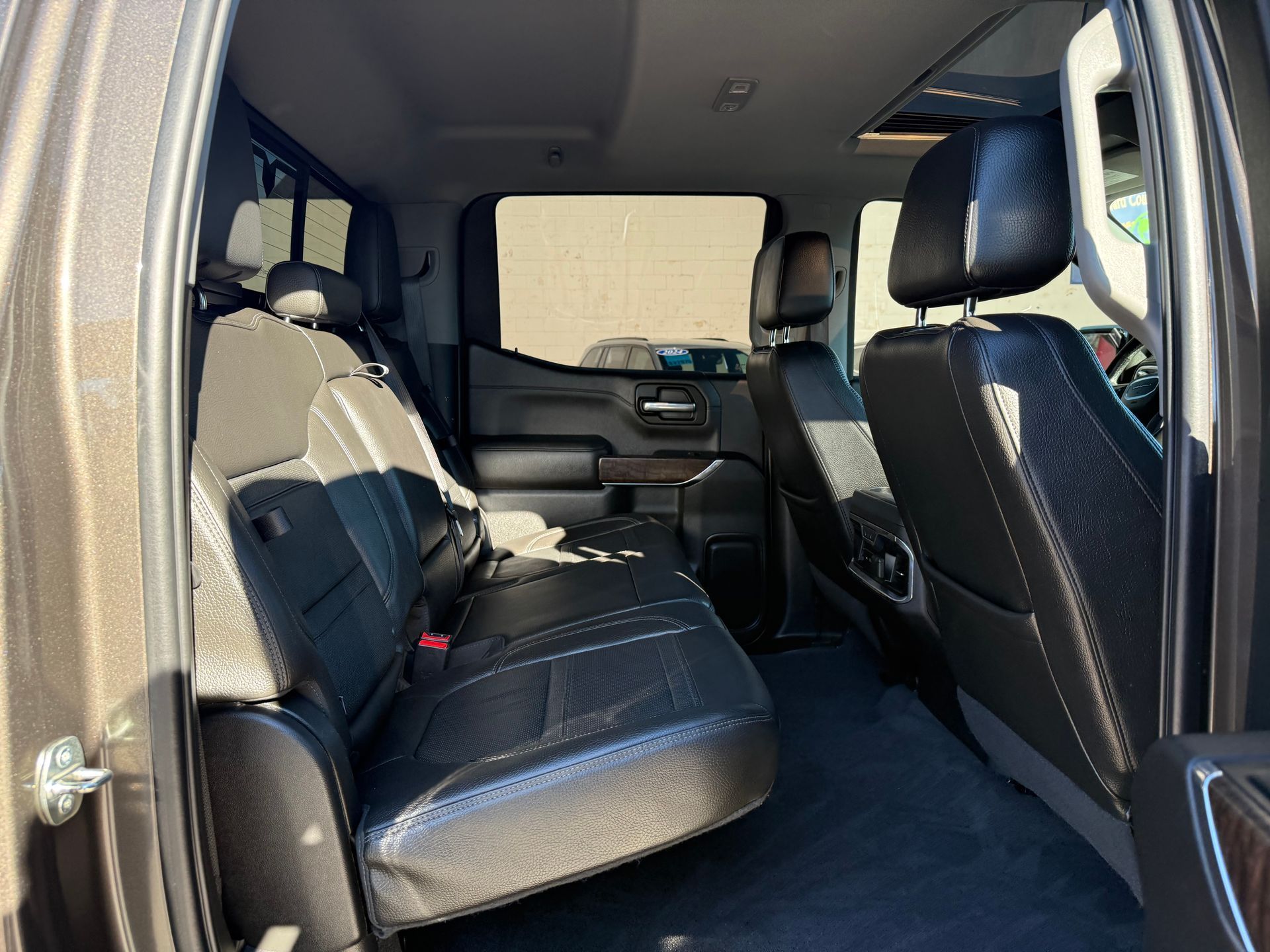 Rear interior view of a brown pickup truck with black leather seating and a clean carpet floor.