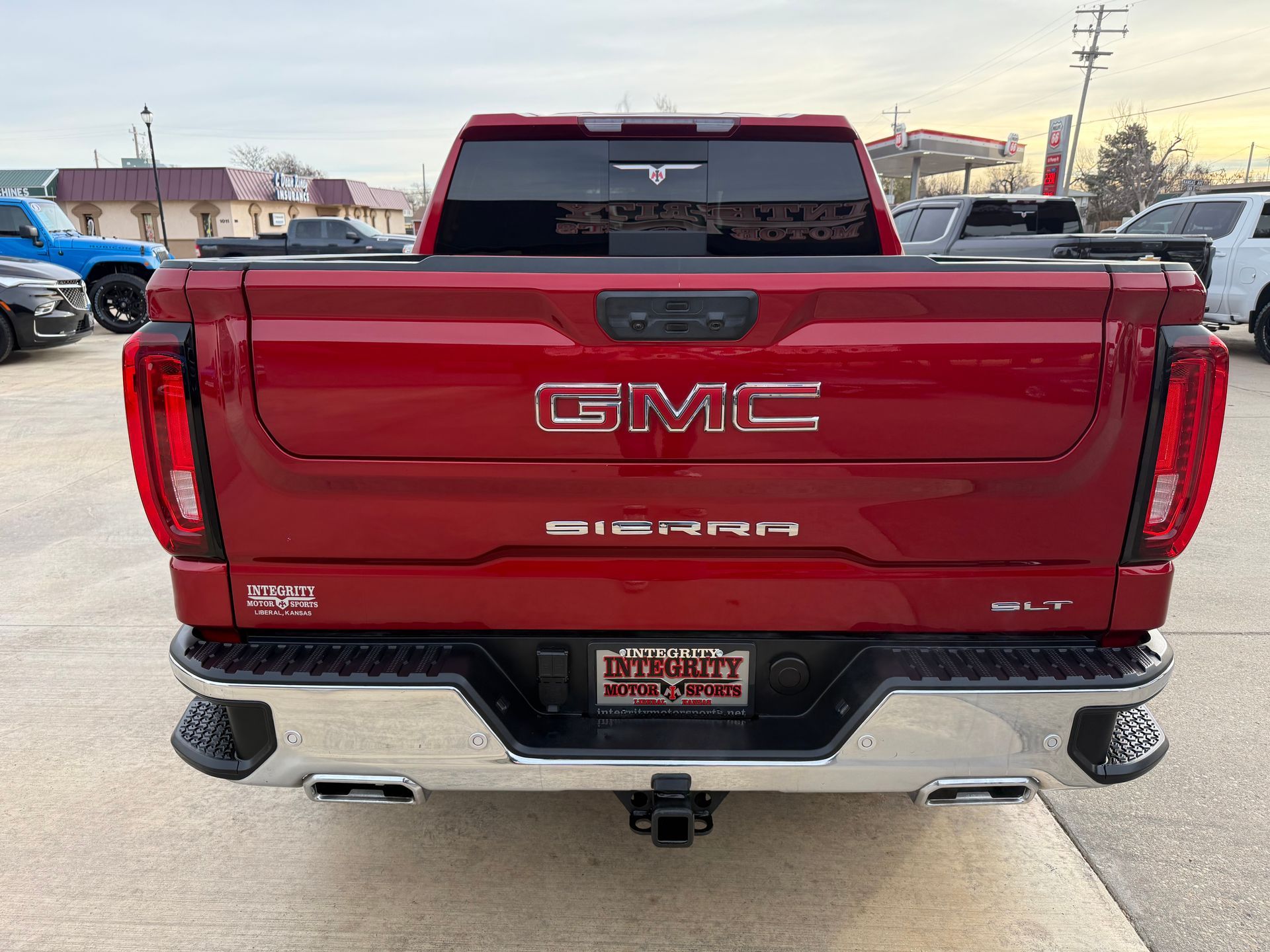 Red GMC Sierra truck rear view with chrome bumper, tow hitch, and tailgate branding.