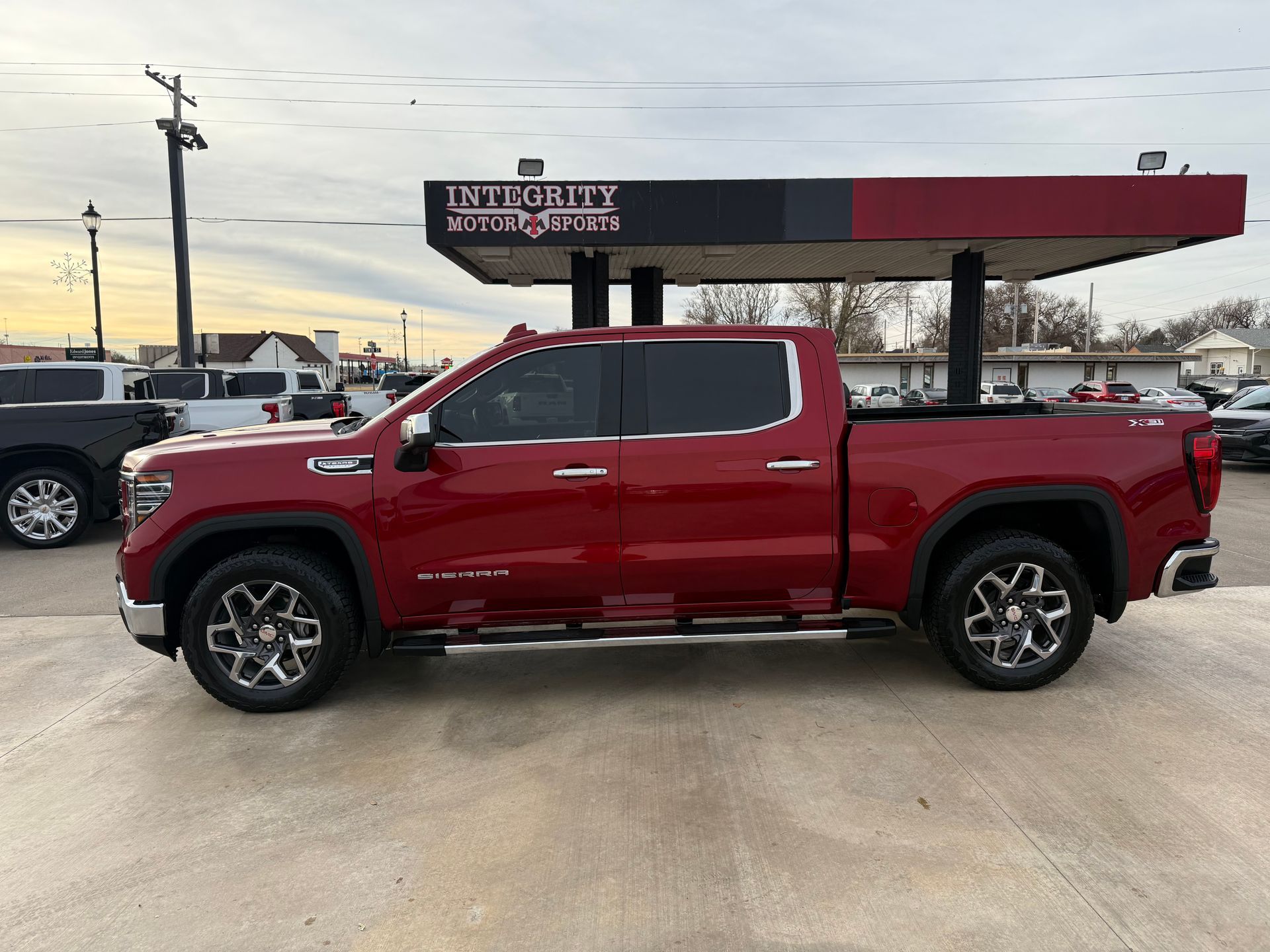 Red GMC pickup truck parked outside a business with a red and black canopy.