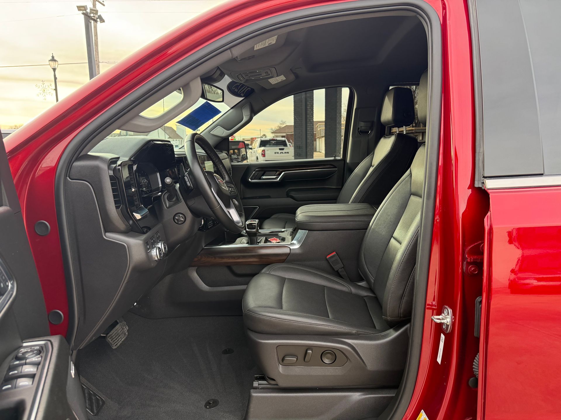 Red truck interior: black leather seats, steering wheel, dashboard, and open door.