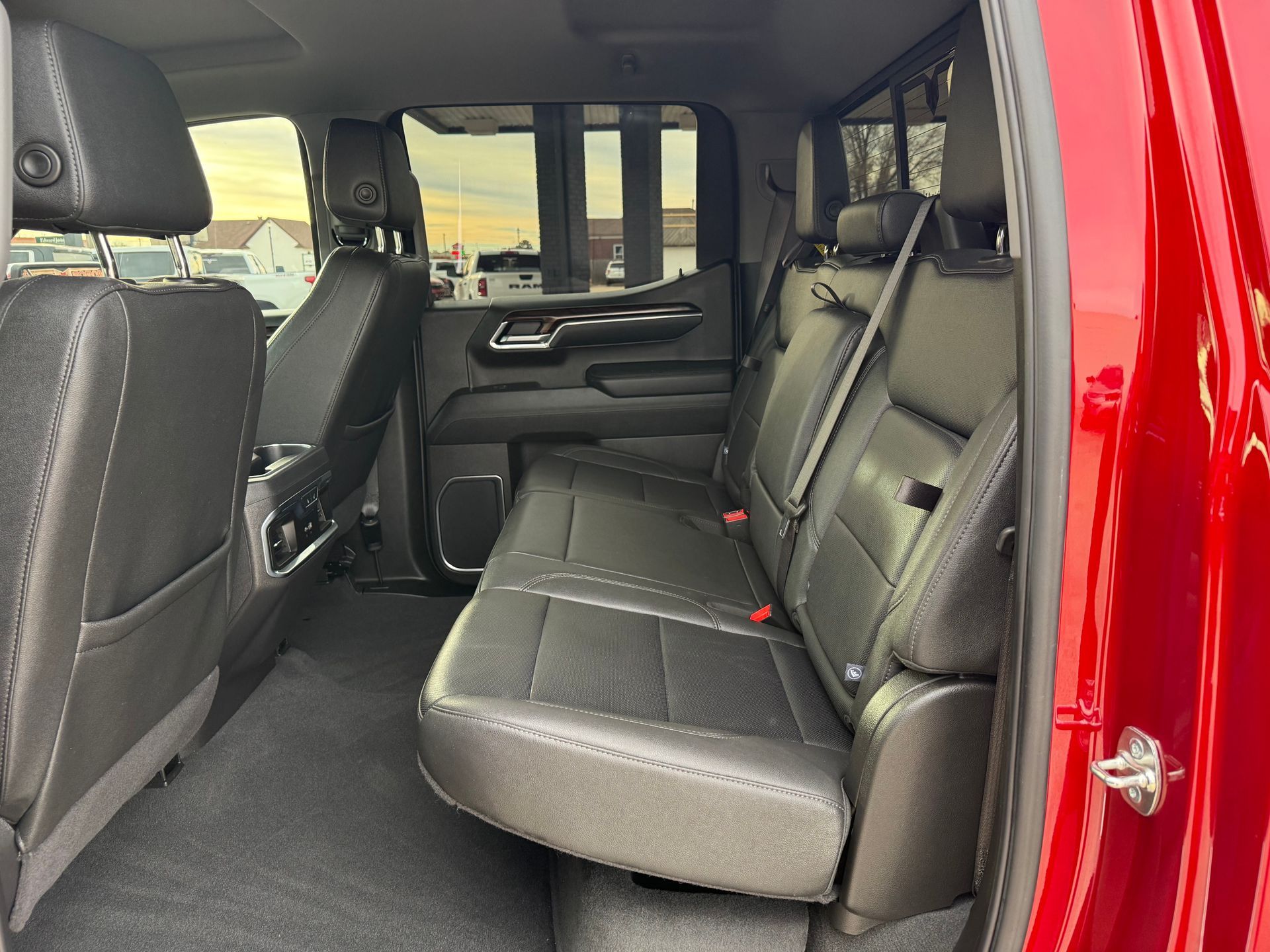 Black leather truck interior with rear seats folded up. Red door frame visible.