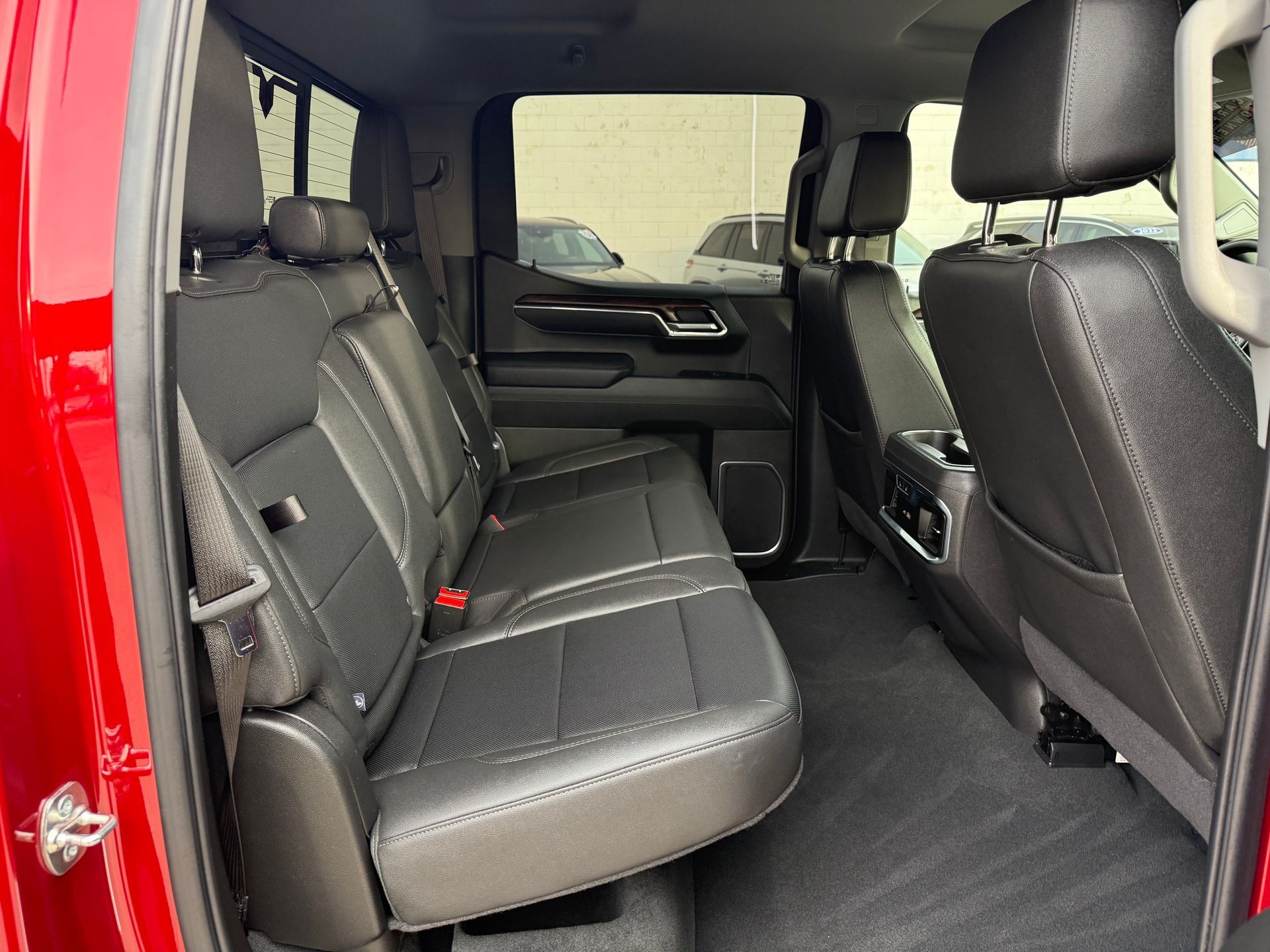 Red truck interior with black leather seats. Back seats are visible, with a central armrest.