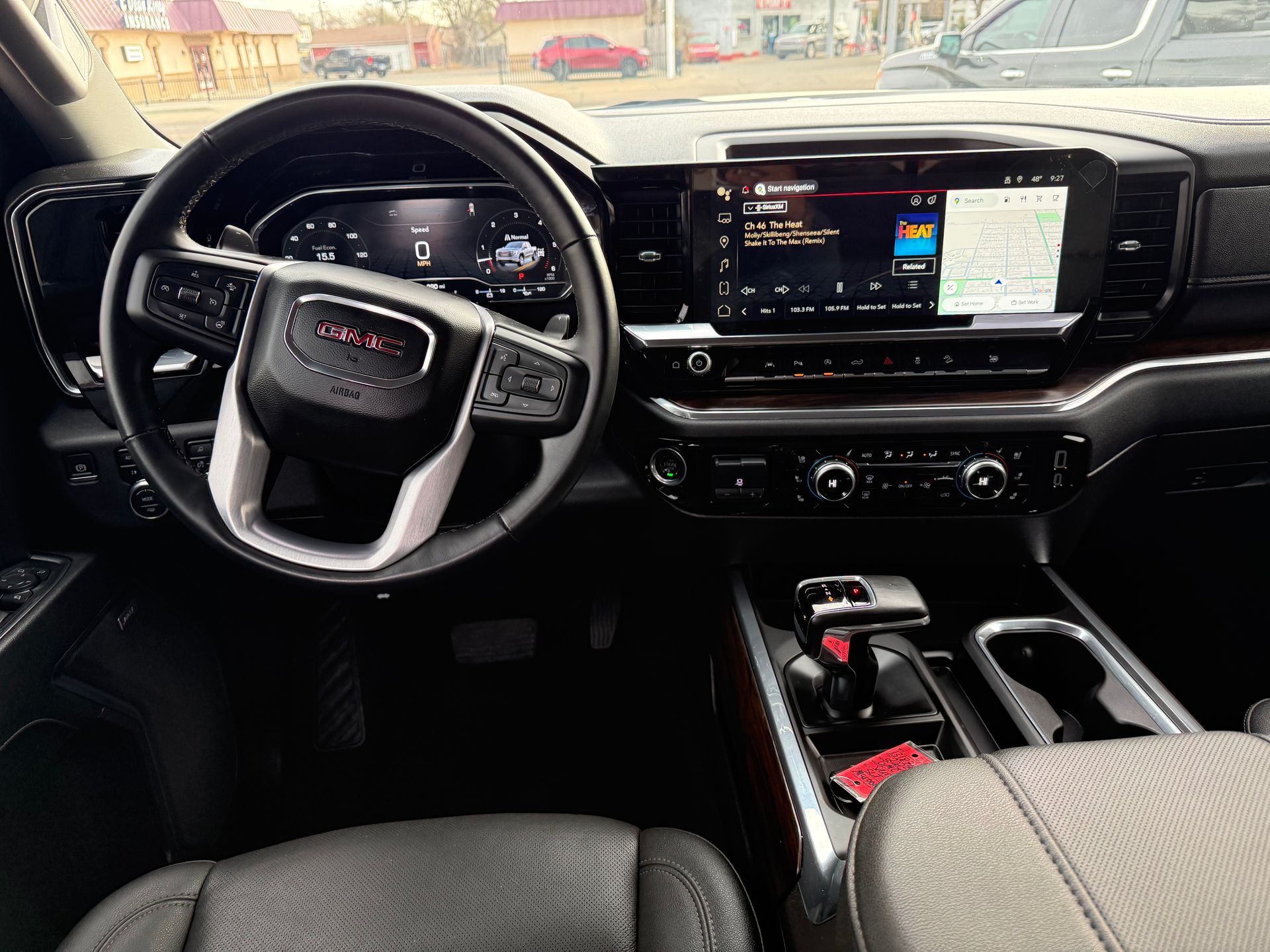 Interior of a GMC truck: black dashboard with steering wheel, infotainment screen, and center console.