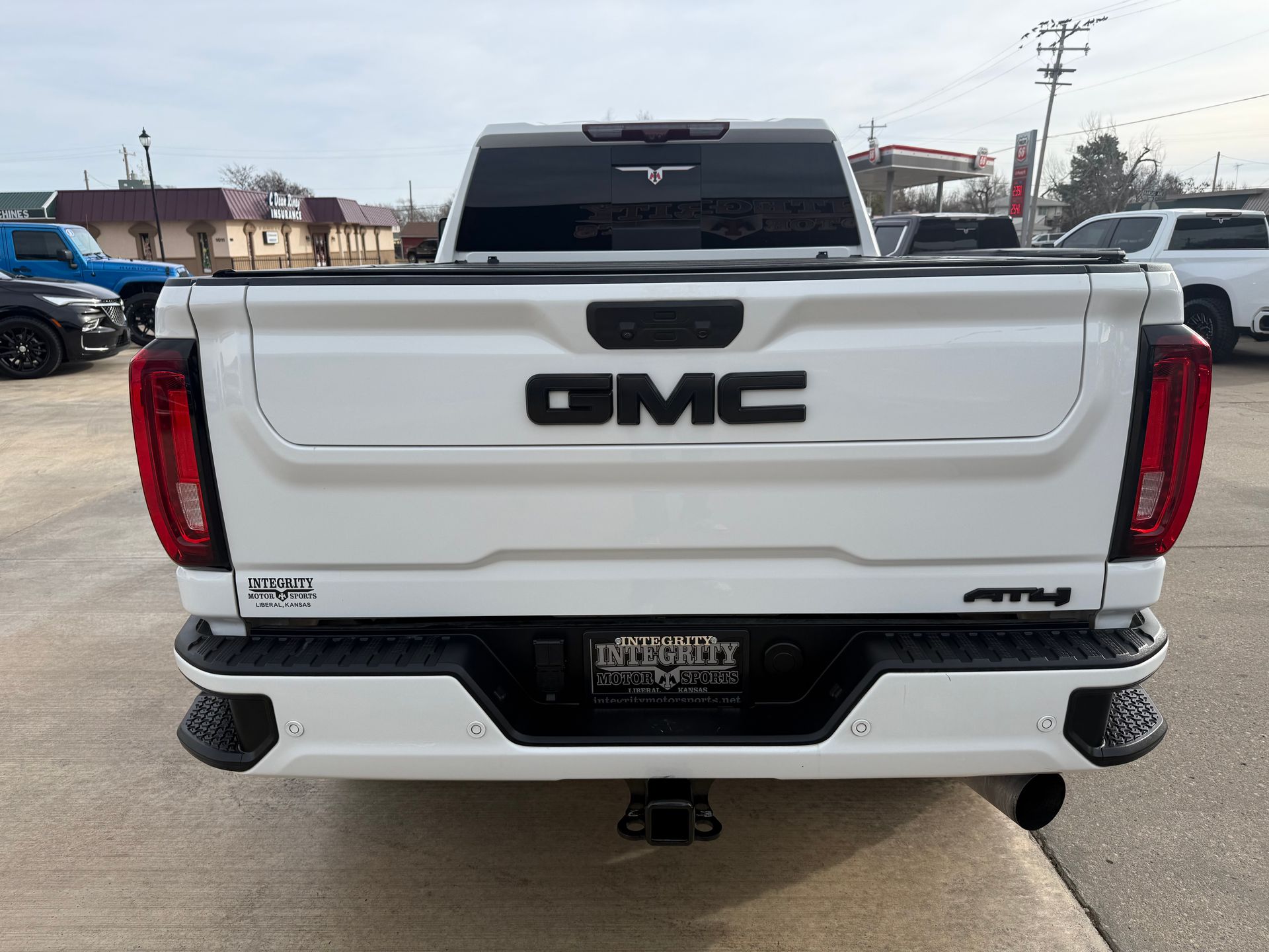White GMC truck rear view, black GMC logo, AT4 emblem, hitch.