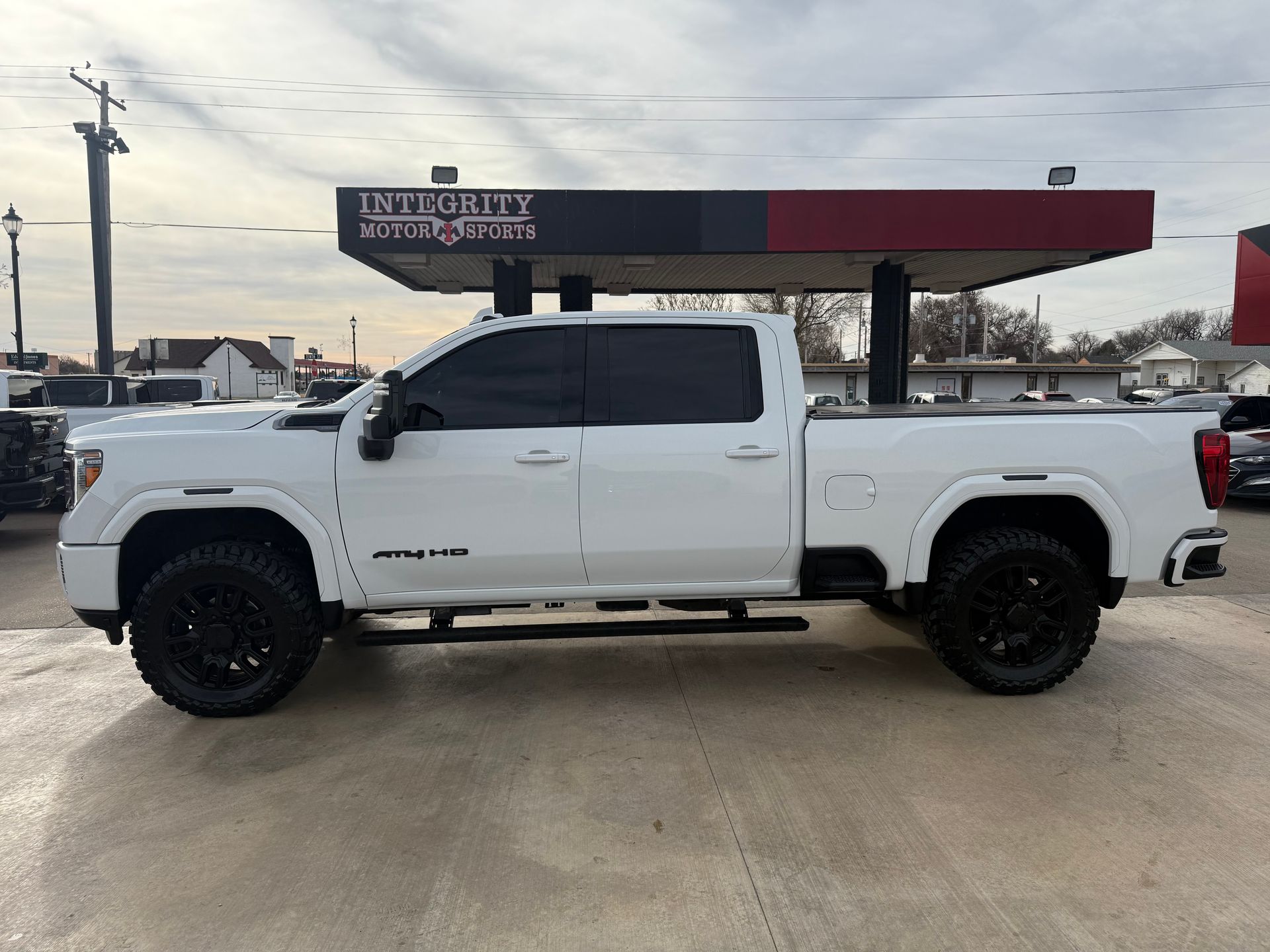 White pickup truck with black wheels parked in front of a building with a red and black awning.