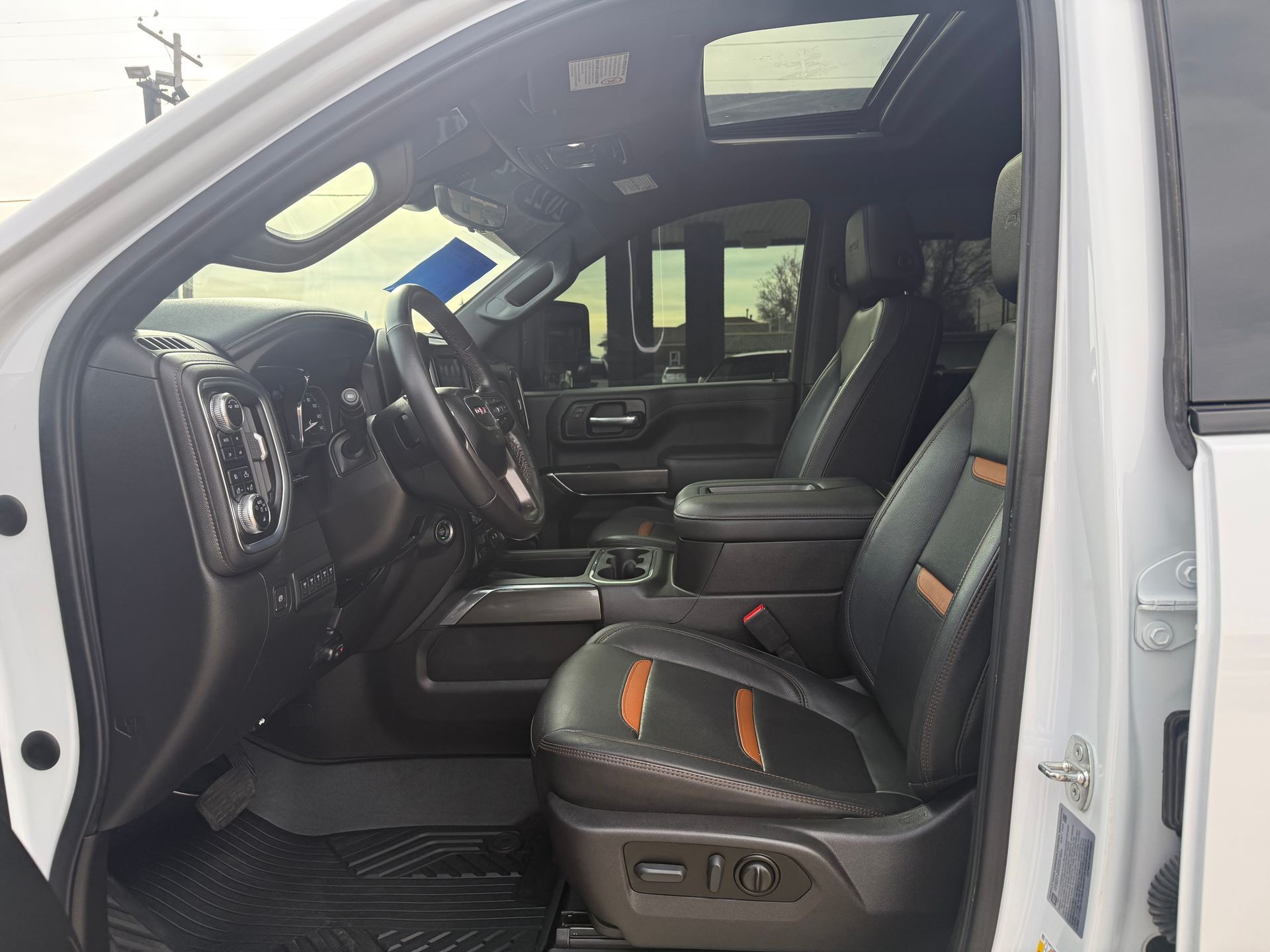 White truck interior with black leather seats, steering wheel, and sunroof.